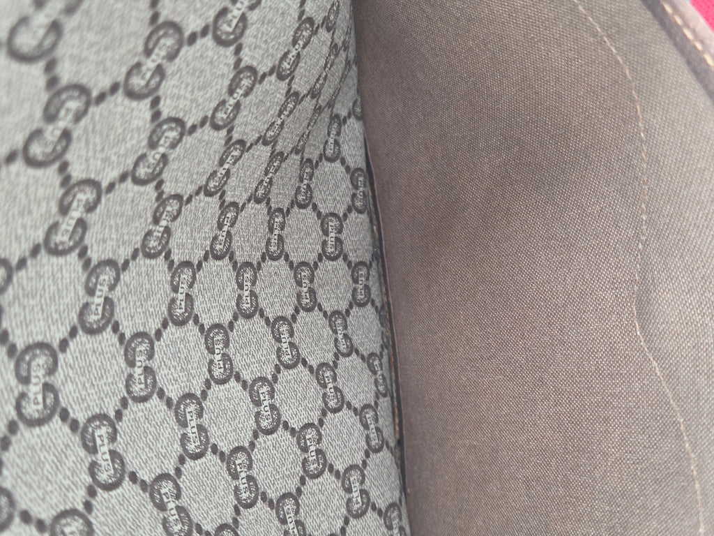Close-up of a gray fabric surface with a repeating interlocking G monogram pattern and a smooth gray side panel.