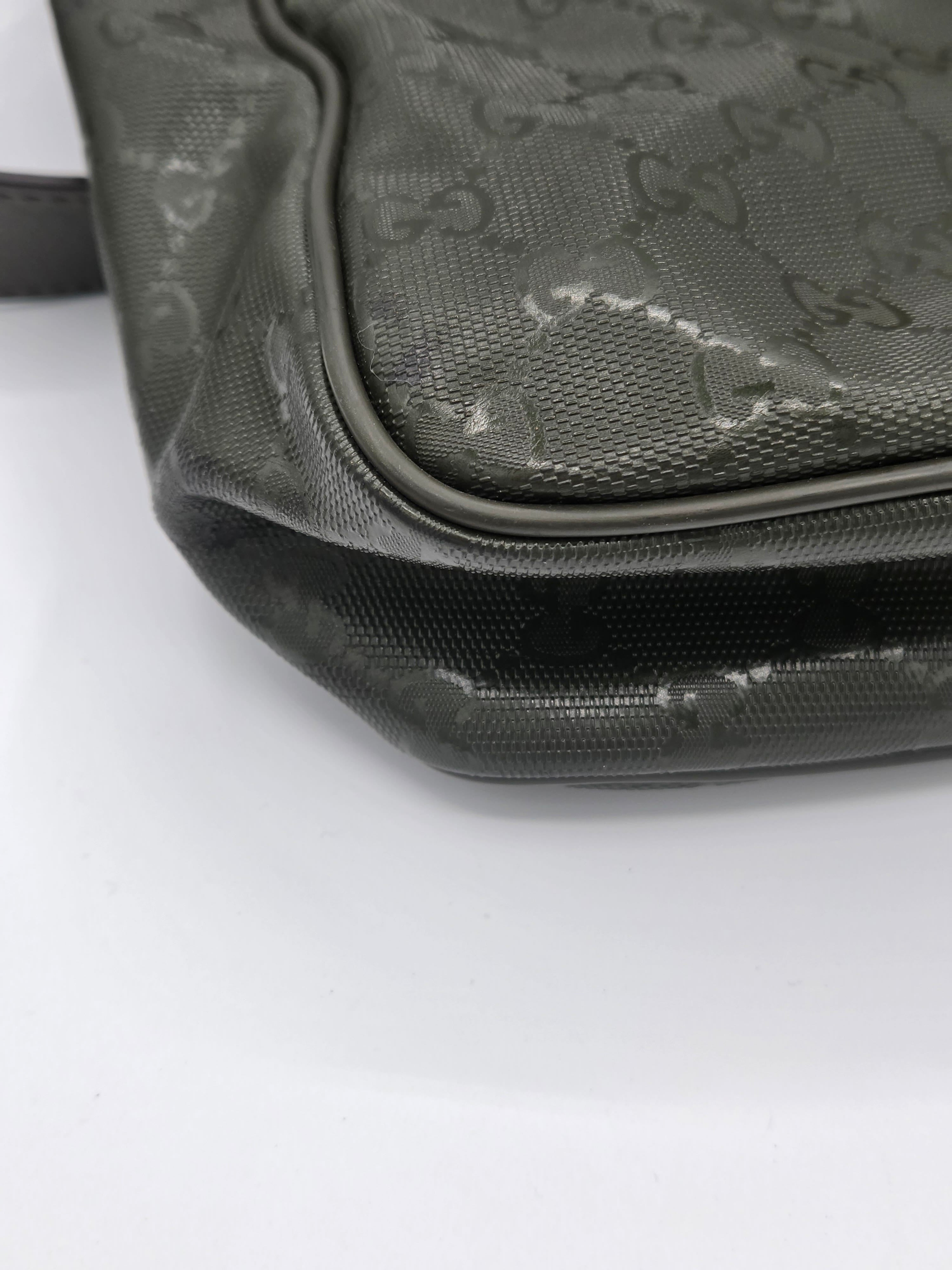 Close-up of a dark gray Gucci monogram coated canvas bag corner with black trim on a white background.