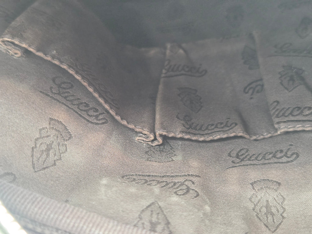 Close-up of a dark gray Gucci fabric with an allover embossed logo pattern and stitched details.