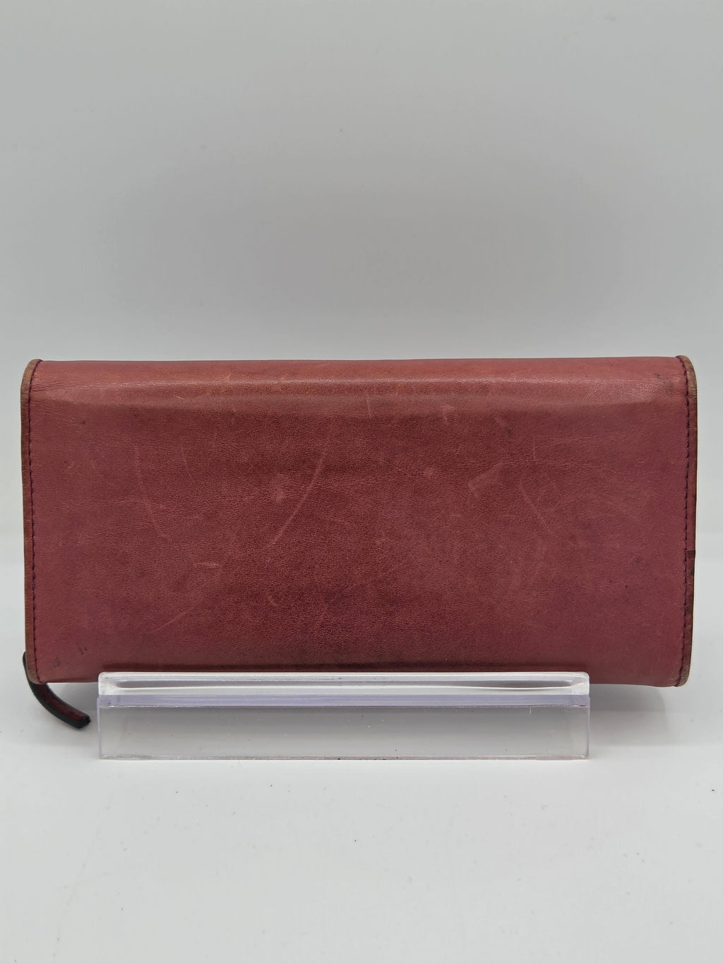 A reddish-brown leather notebook cover with a clear plastic sleeve attached on the side, shown against a plain light gray background.