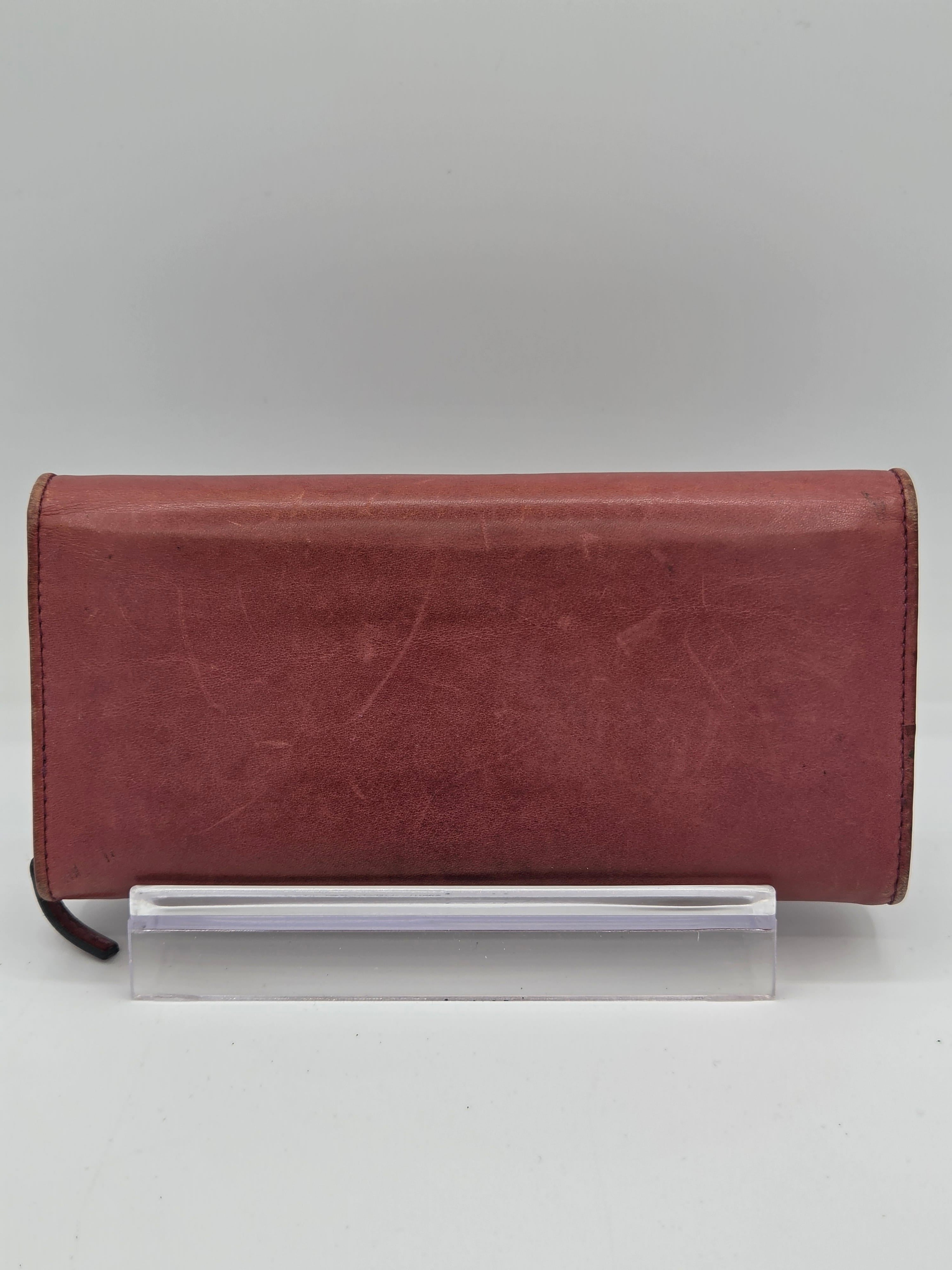 A reddish-brown leather notebook cover with a clear plastic sleeve attached on the side, shown against a plain light gray background.