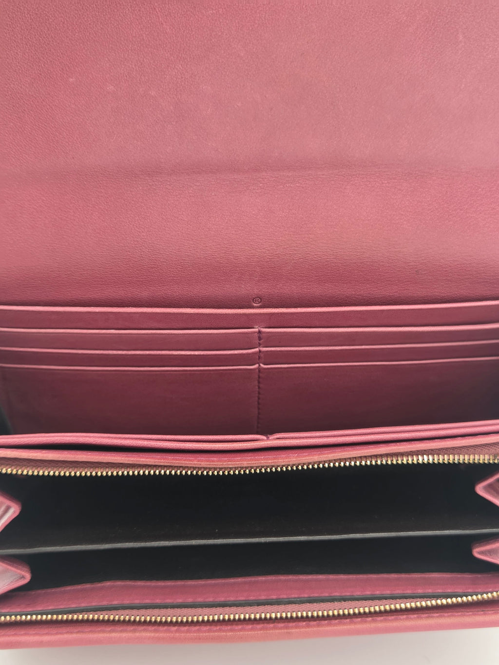Close-up of the interior of a pink leather wallet or clutch, showing multiple card slots, a black interior lining, and a gold-tone zipper.