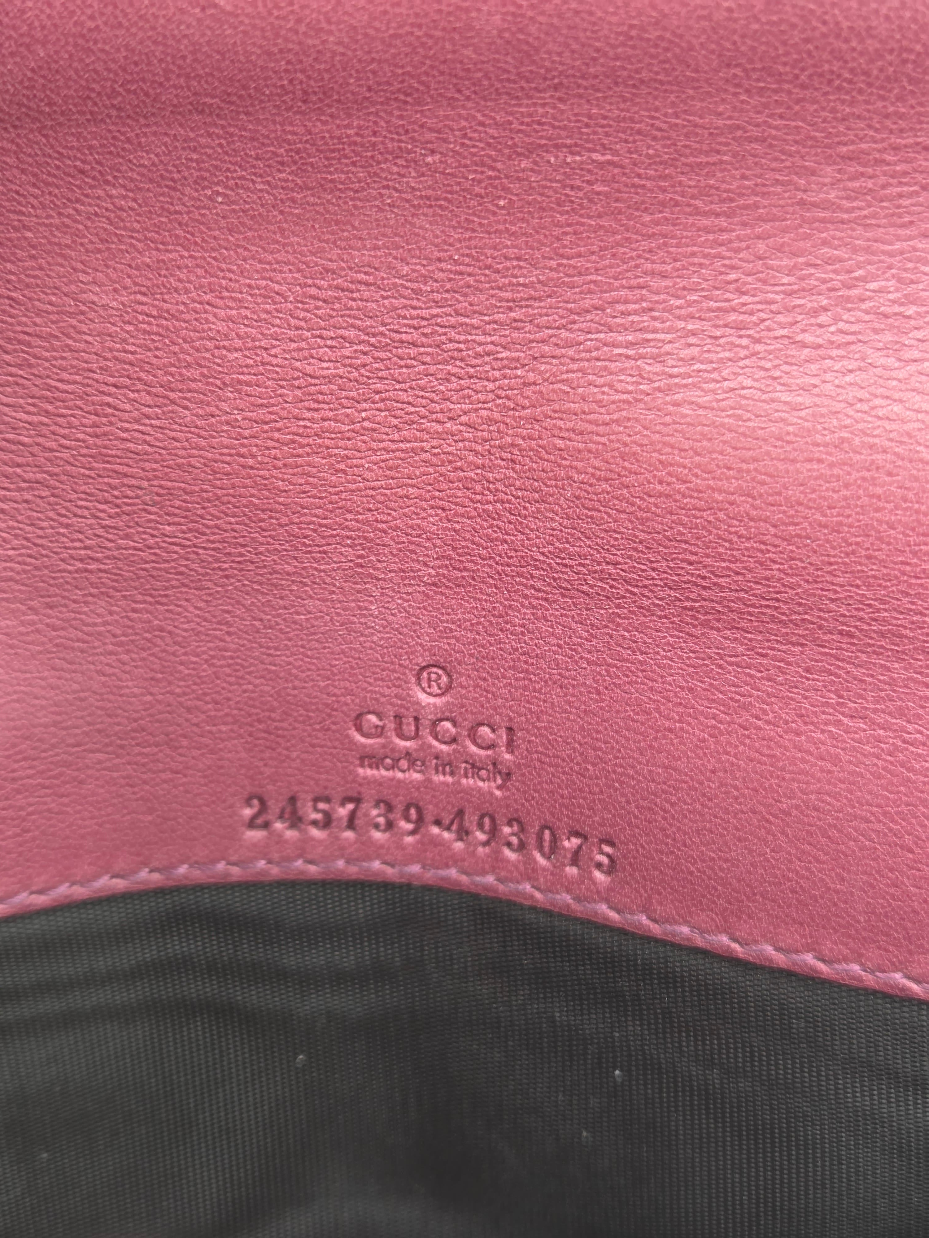 Close-up of a pink leather surface with embossed Gucci text and a black fabric section at the right edge.