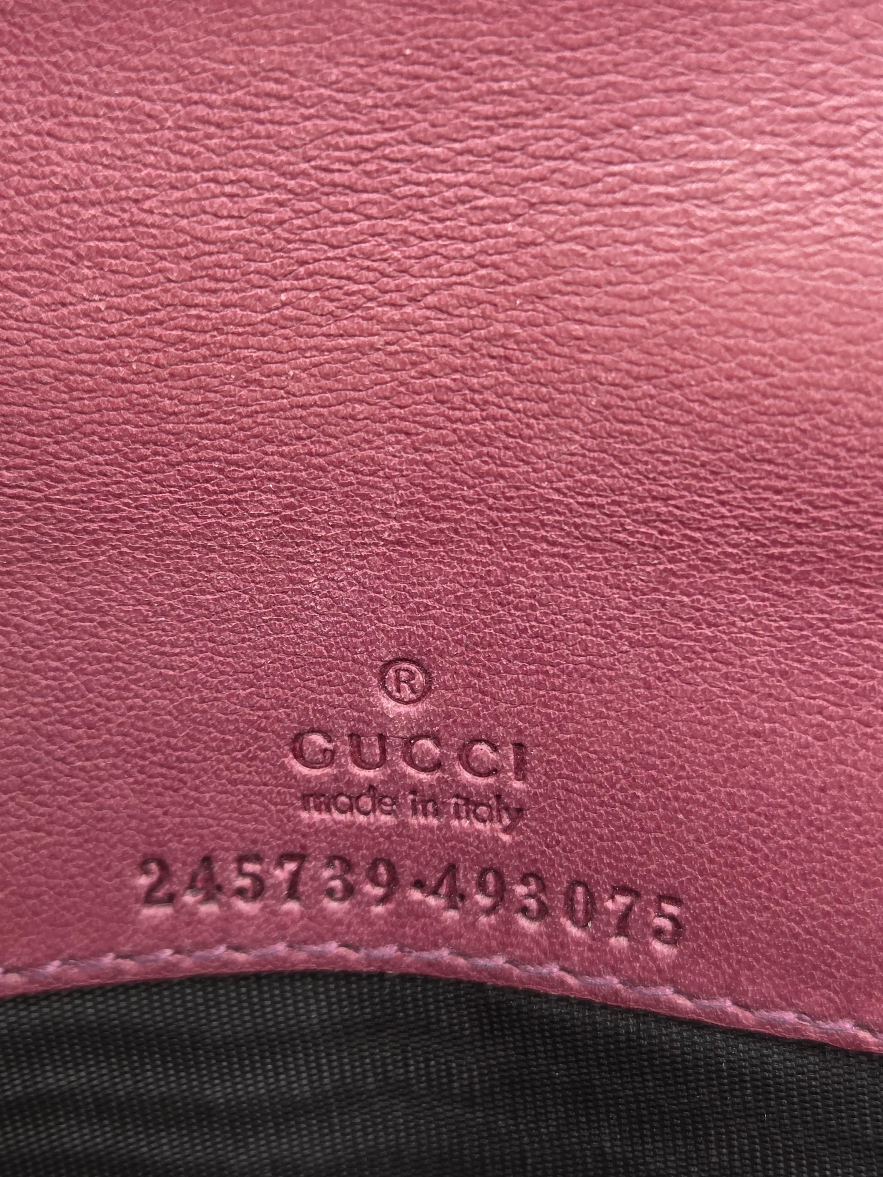 Close-up of a pink textured leather surface with an embossed GUCCI logo and 'made in Italy' text, next to a black fabric section.