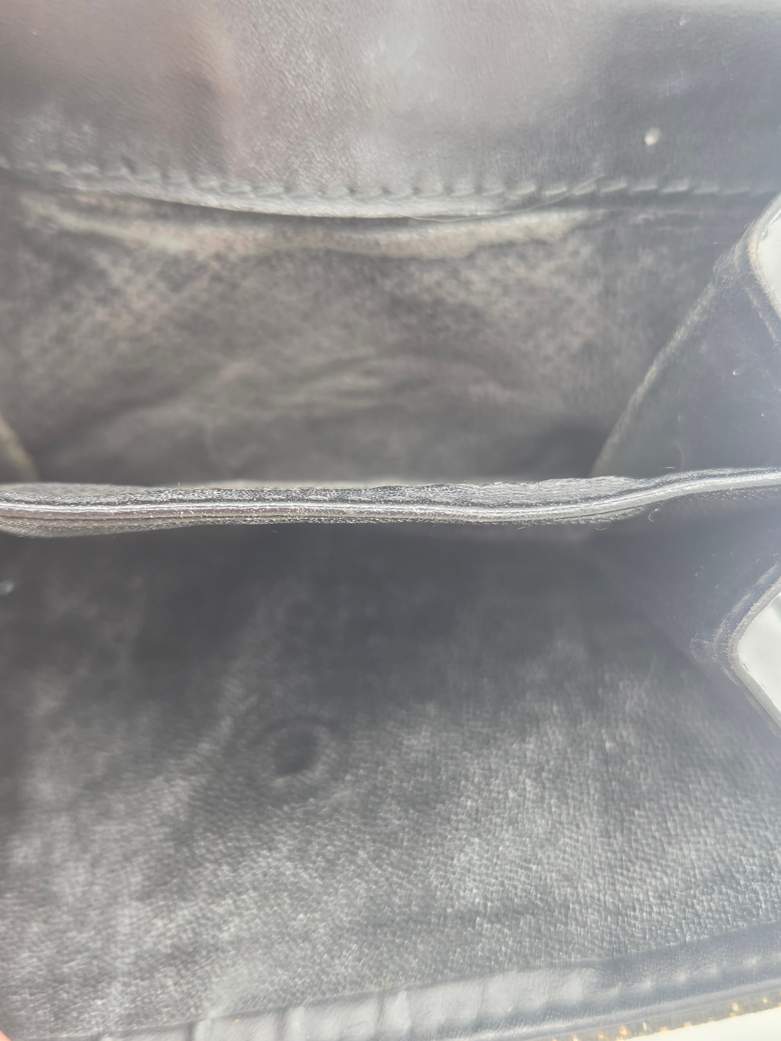 Close-up of the interior lining of a black leather or faux-leather bag, showing the dark textured fabric and zipper edge.