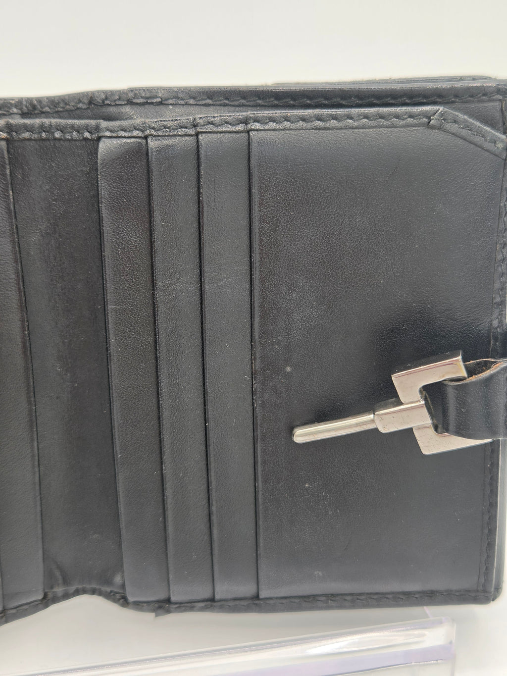 A close-up of a black leather wallet or card holder with multiple card slots and a silver metal clasp, shown against a plain light background.