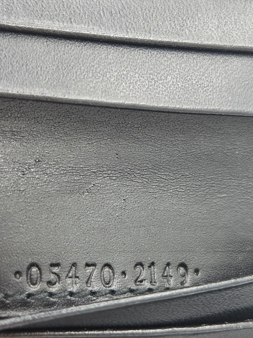 Close-up of a dark gray textured material with embossed vertical ridges and a stamped numeric marking reading 05470-2149.