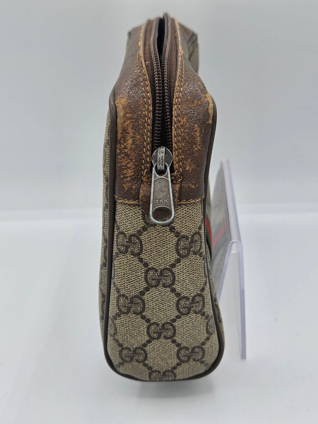 A Gucci zippered pouch in the brand's classic GG Supreme canvas, featuring a brown leather trim and a silver-tone metal zipper pull.