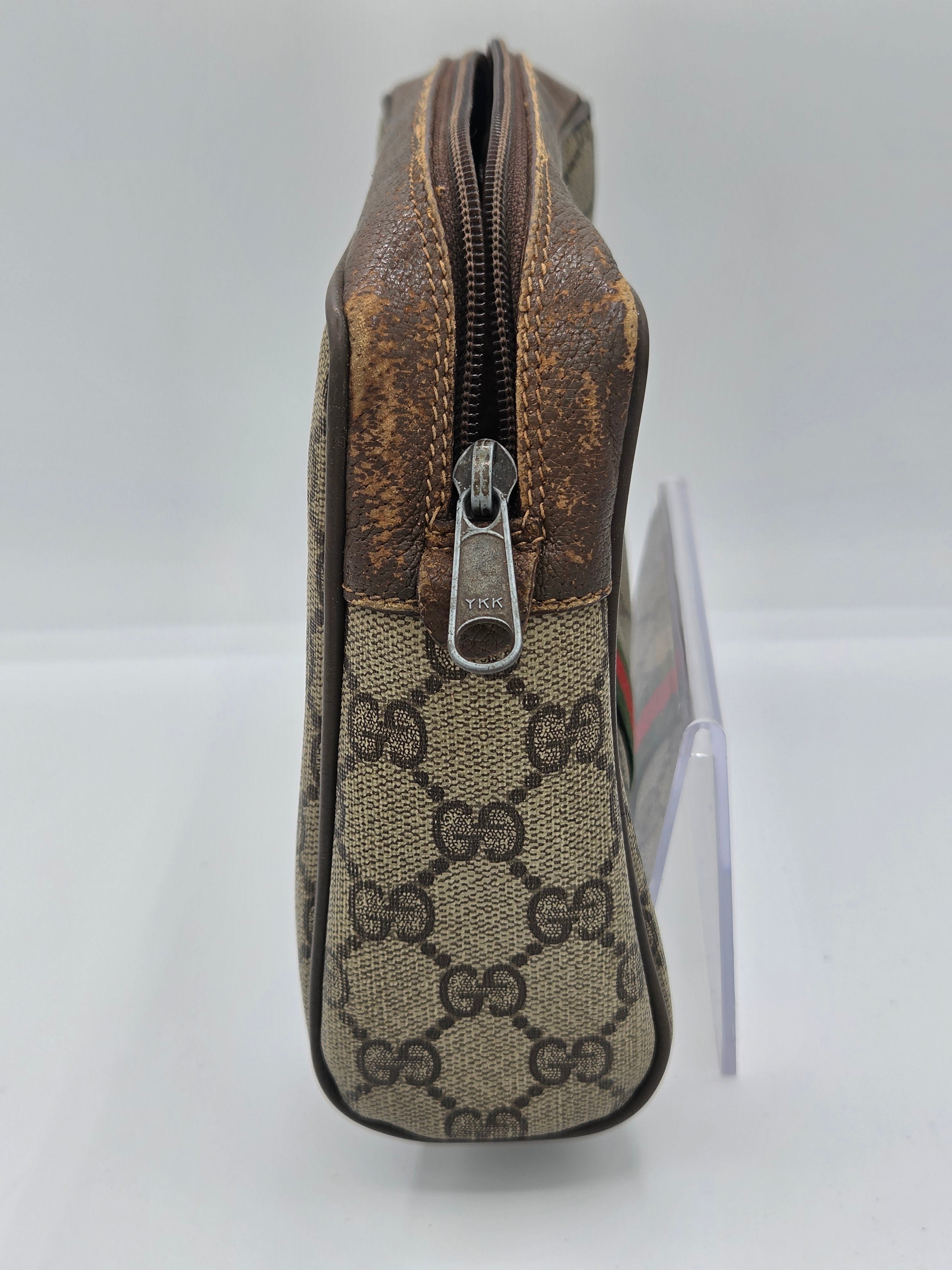 A Gucci zippered pouch in the brand's classic GG Supreme canvas, featuring a brown leather trim and a silver-tone metal zipper pull.