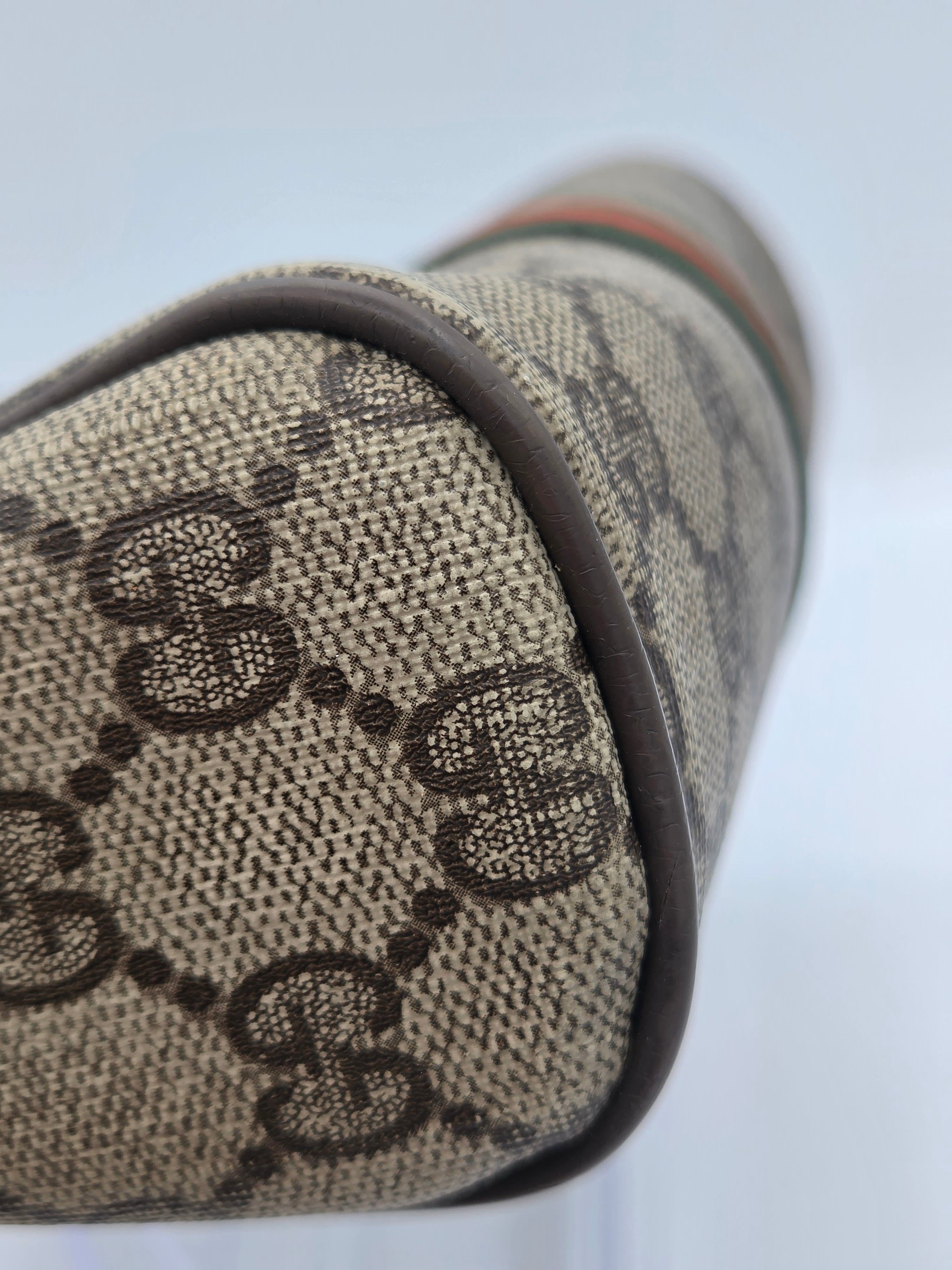 Close-up of a Gucci bag made of beige GG Supreme canvas with dark brown monogram pattern and a dark brown leather trim.