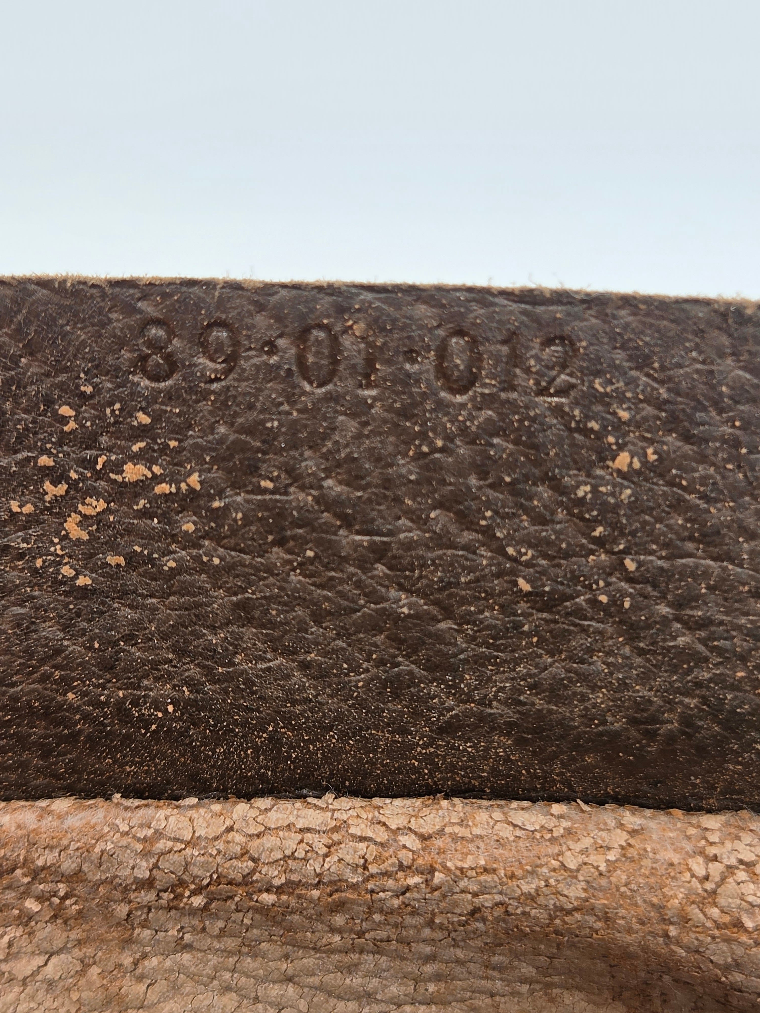 Close-up of a dark brown textured leather strap or material with embossed numbers '89-01-02' on the left side, next to a lighter tan textured surface.