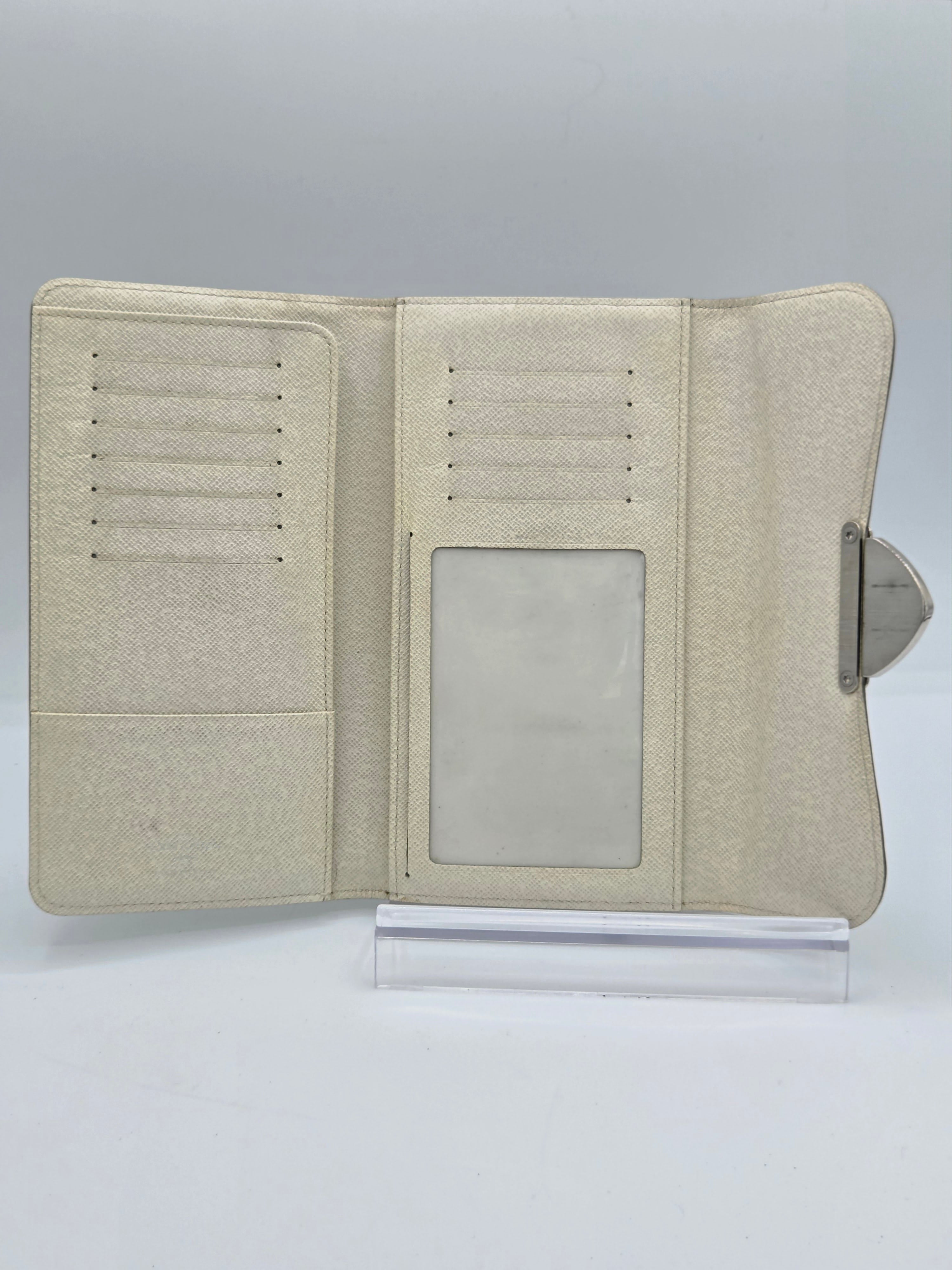 A light beige textured faux-leather passport holder or organizer case shown open, featuring card slots, a clear ID window, and a silver metal clip at the top, set against a plain white background.