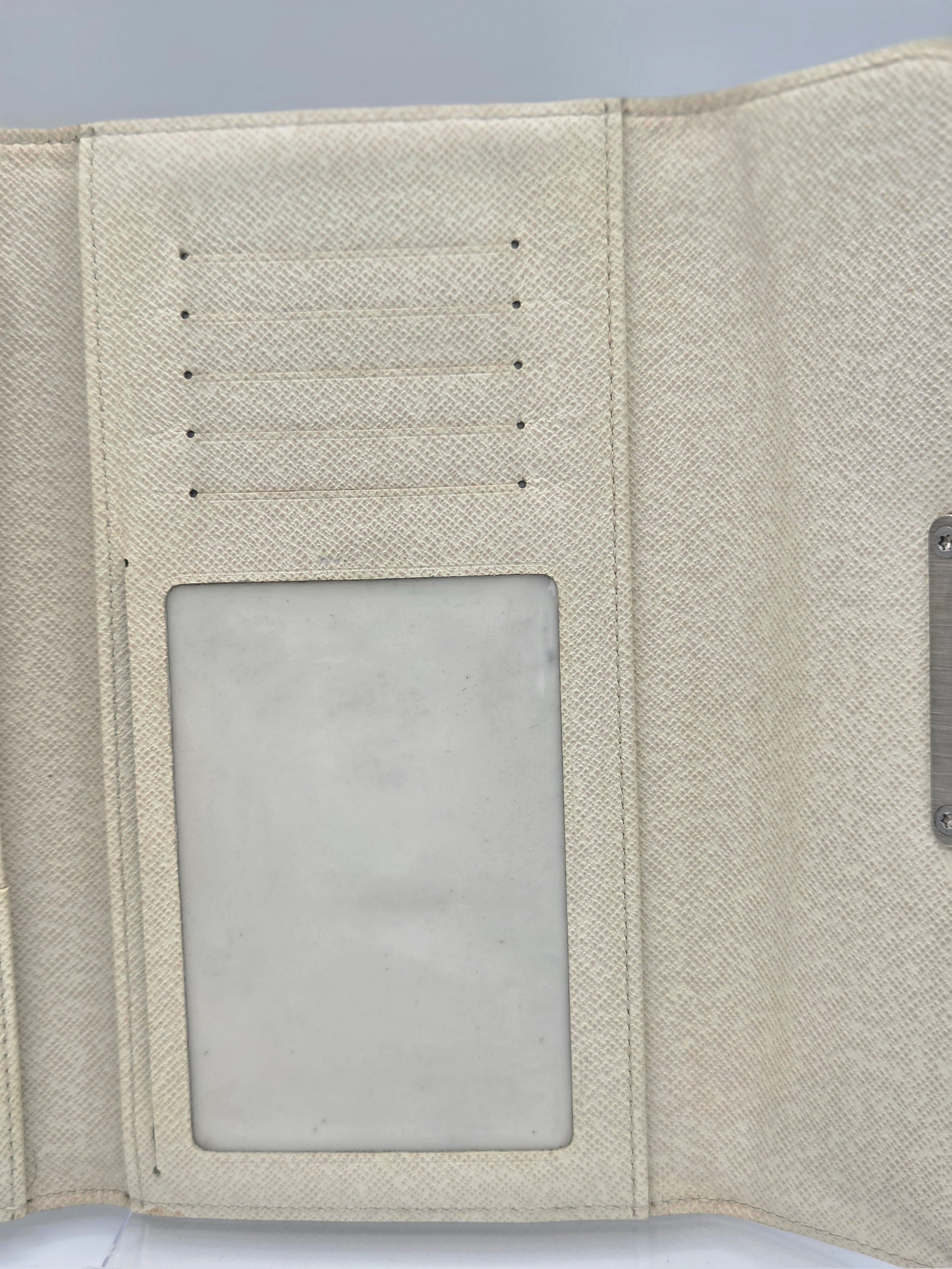 Close-up of the interior of a textured cream-colored wallet or organizer, showing card slots on the left and a clear ID window on the right.