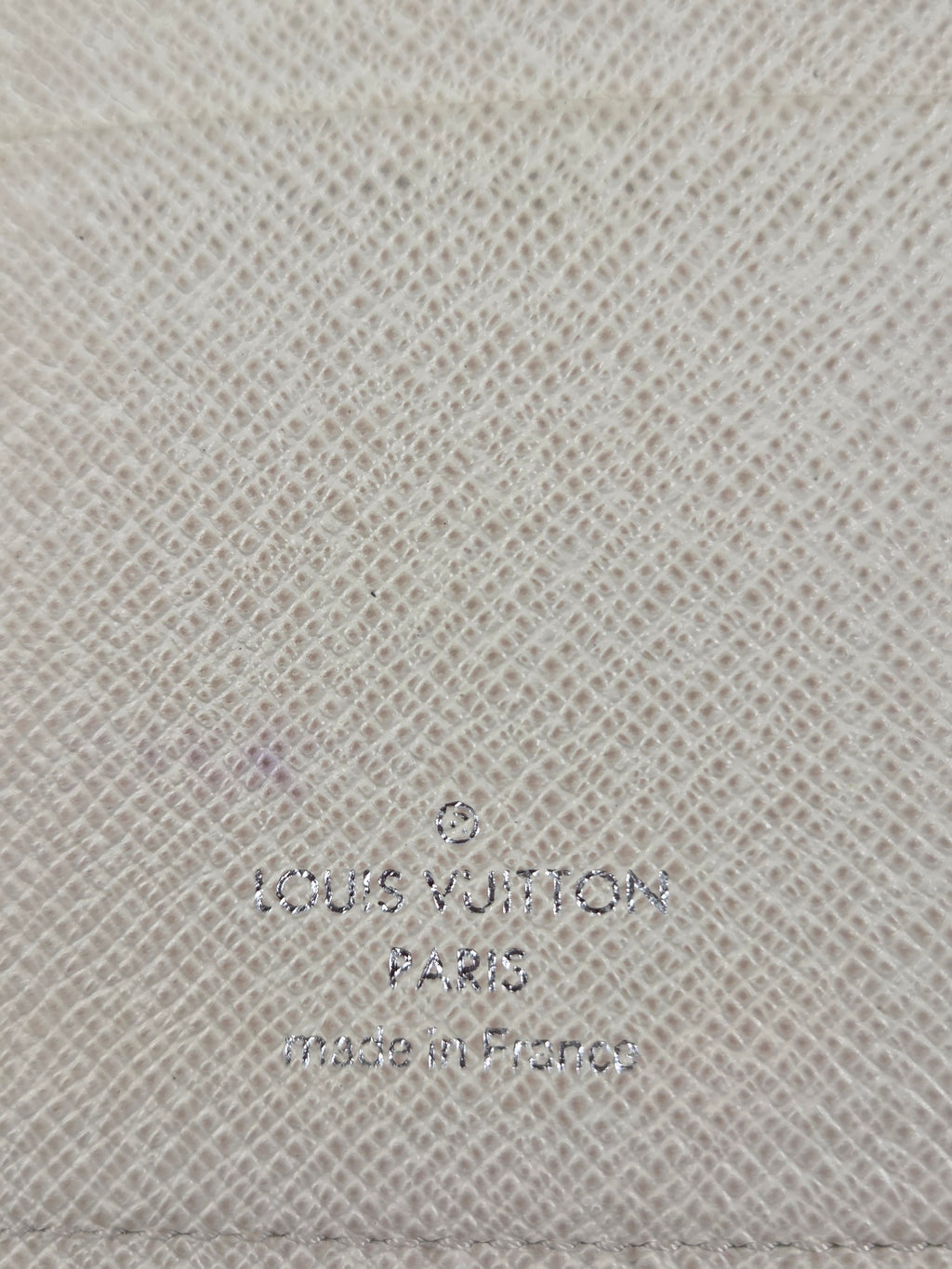 Close-up of a light beige woven fabric texture with faint embossed or printed Louis Vuitton text visible on the right side.