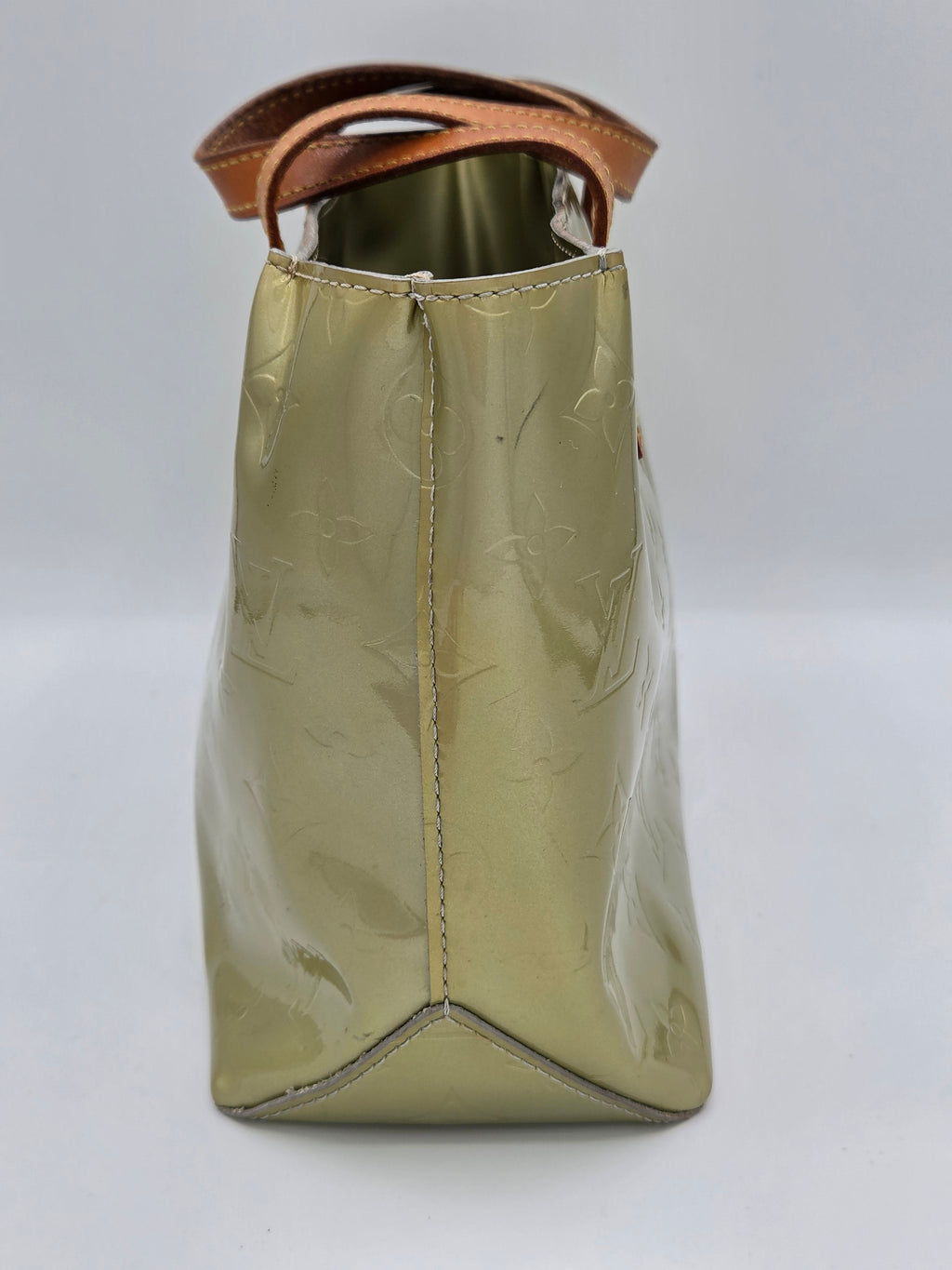 A Louis Vuitton shoulder bag in glossy olive green patent leather with the brand's signature embossed monogram pattern, featuring a brown leather strap visible on the left side.
