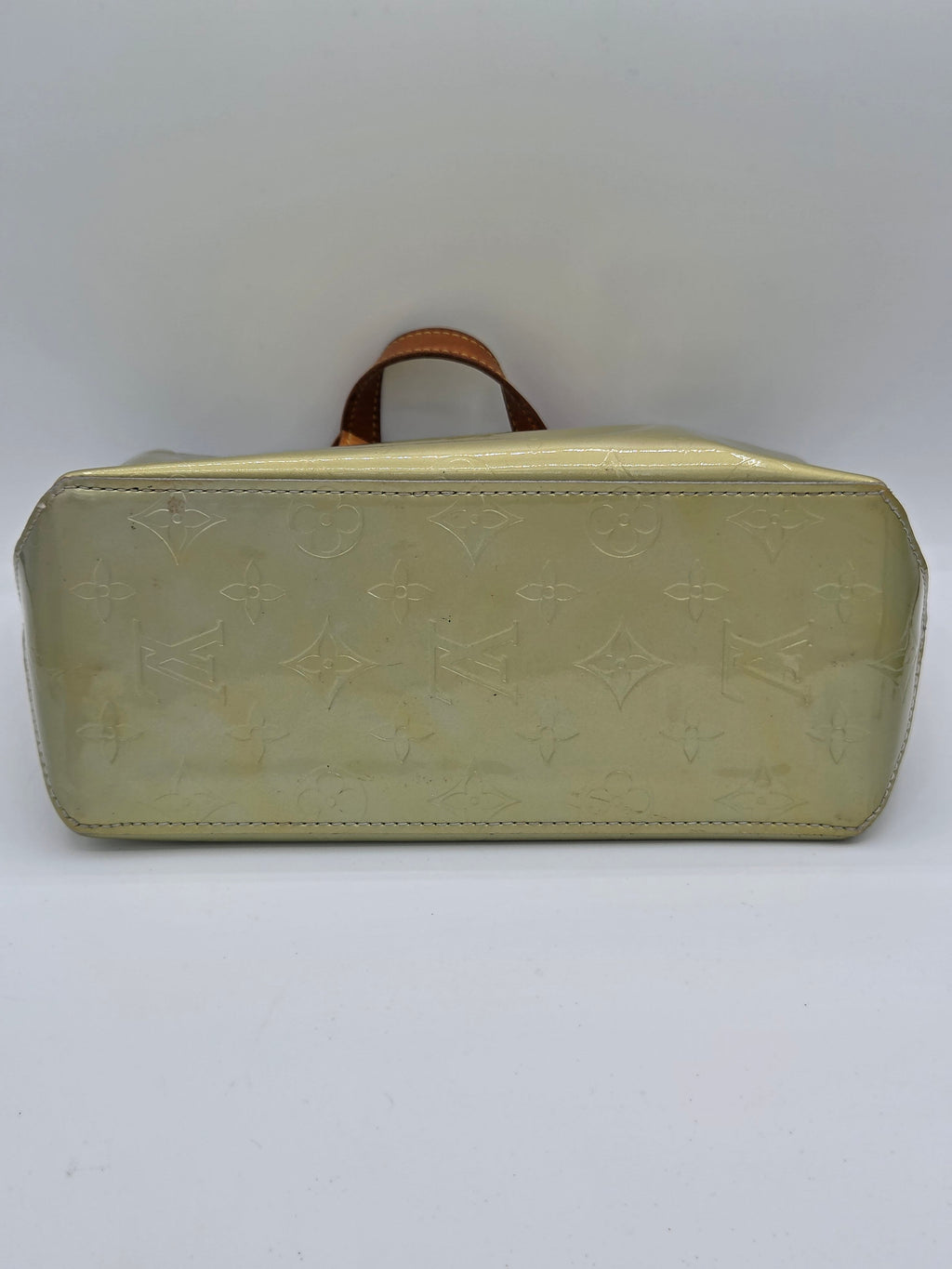 A Louis Vuitton monogram coated canvas bag in a pale yellow-green color, featuring a brown leather top handle, photographed against a plain white background.