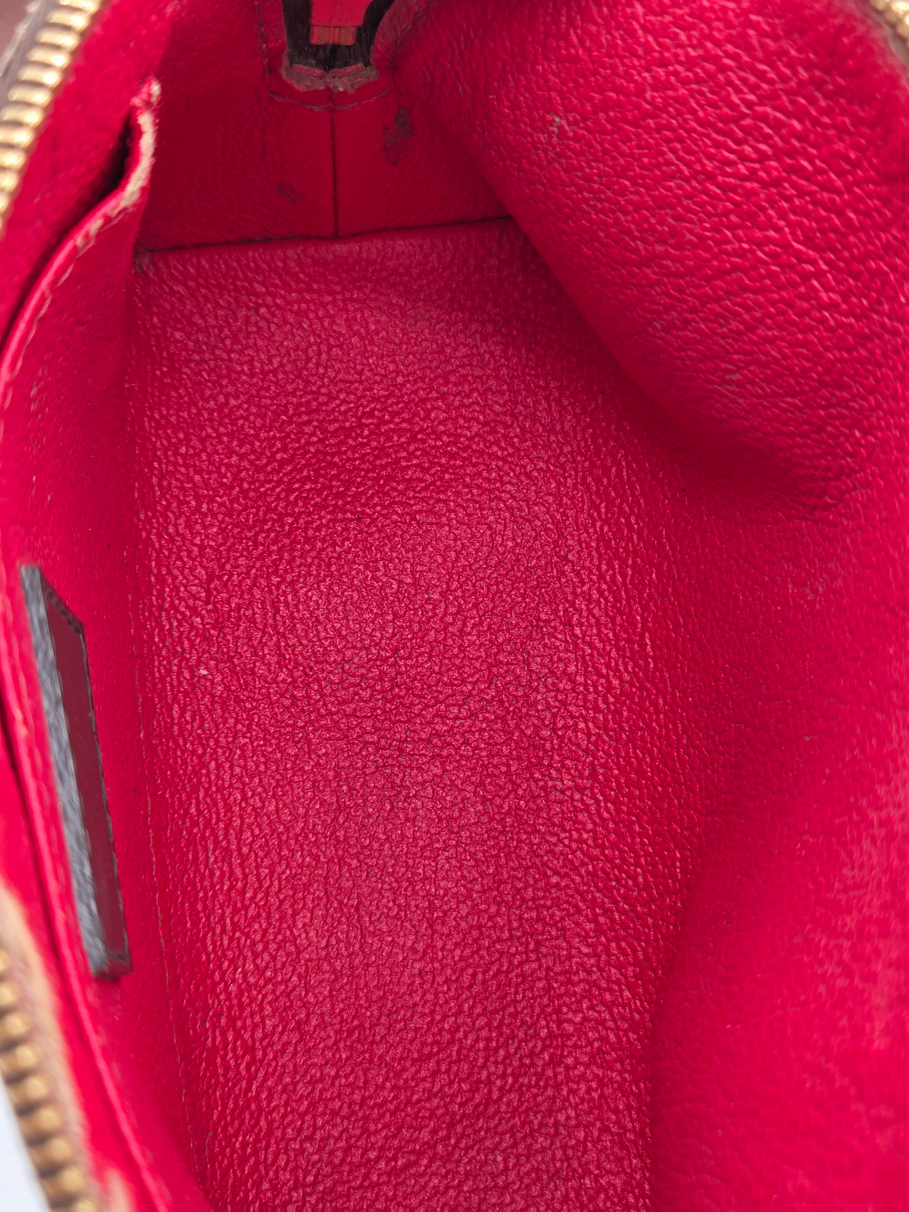 Close-up of the interior lining of a red textured leather pouch or clutch, showing the pebbled leather texture and a gold zipper edge at the bottom.