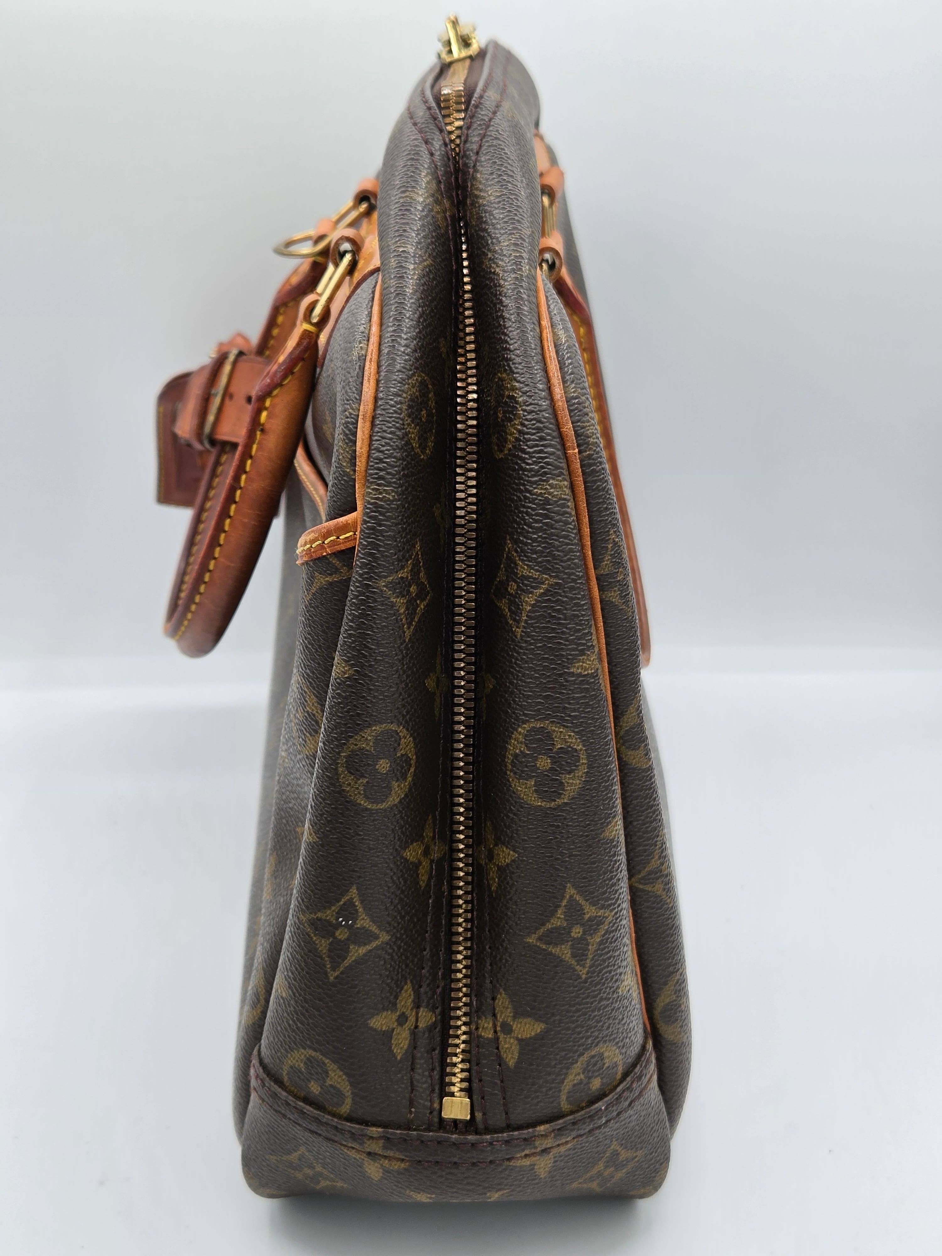 A Louis Vuitton monogram canvas handbag shown from a side profile view, featuring the classic dark brown and tan pattern with gold-tone hardware.