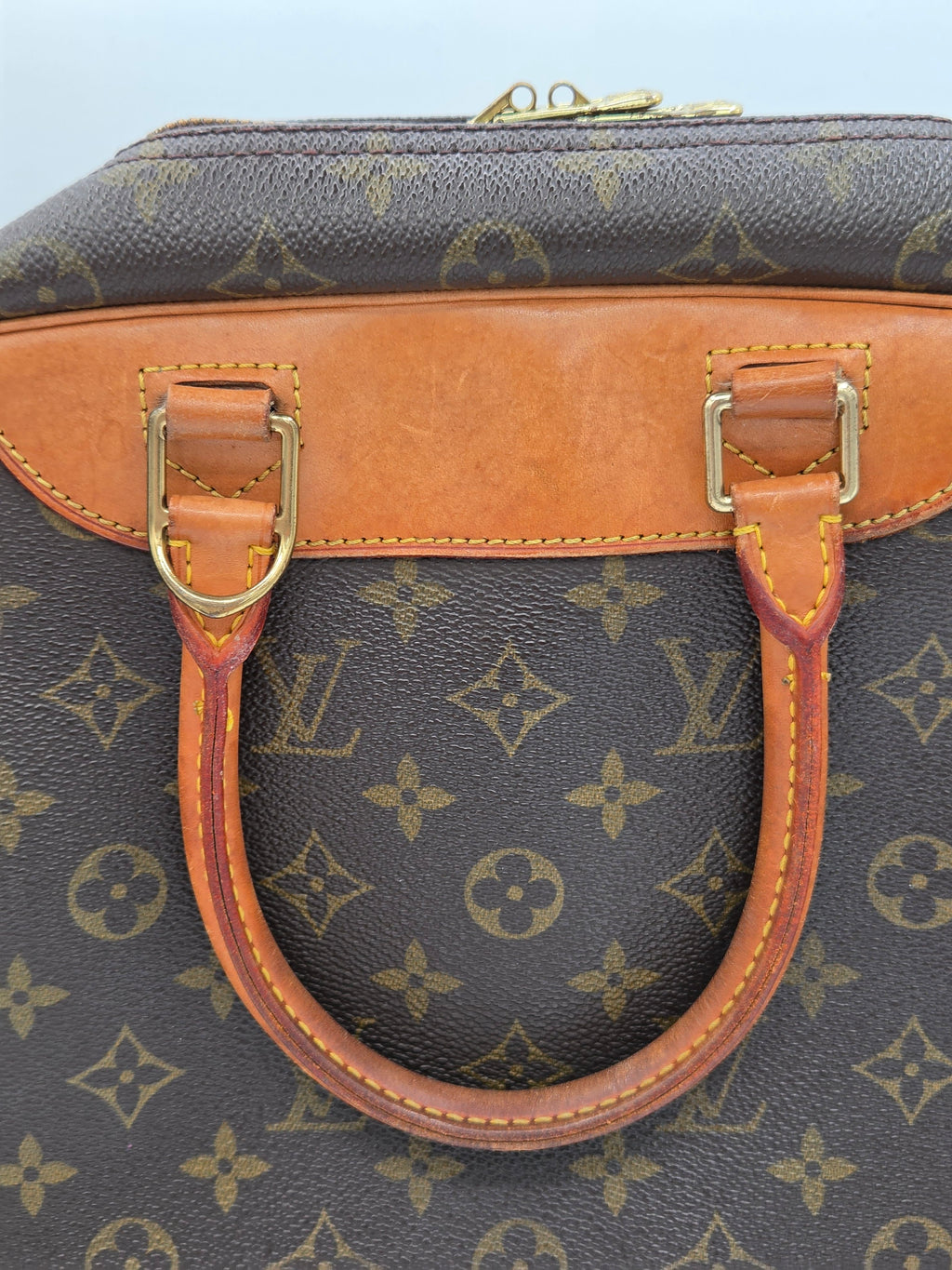 Close-up of a Louis Vuitton handbag in brown monogram canvas with tan leather trim and gold-tone hardware.