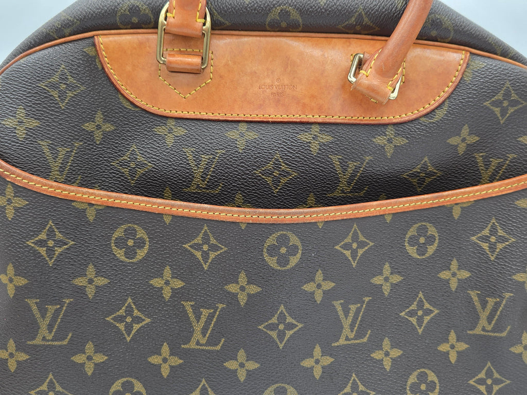 Close-up of a Louis Vuitton monogram canvas bag with tan leather trim and gold-tone hardware.