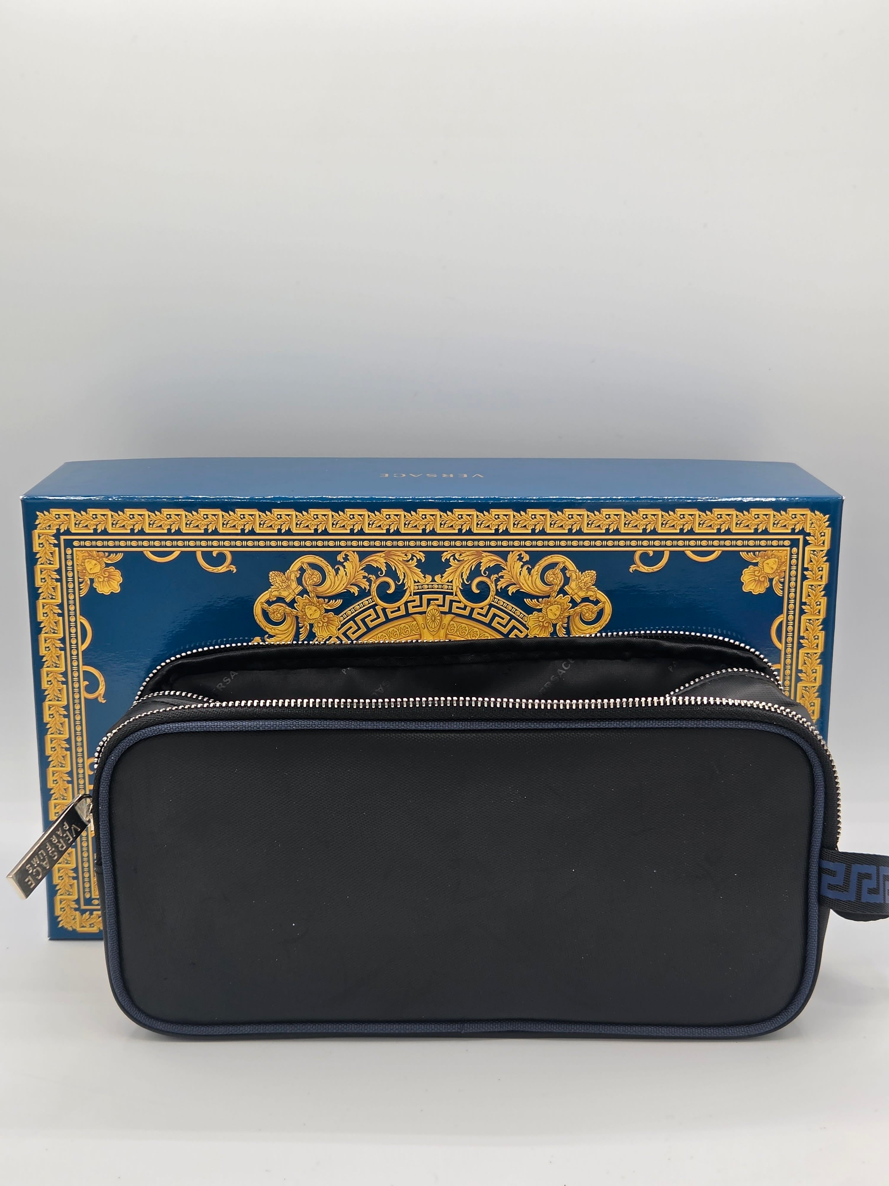 A black zippered cosmetic pouch with a silver zipper, displayed in front of its blue and gold Versace branded box on a light gray background.