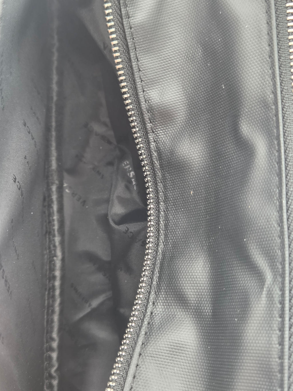 Close-up of a black nylon bag showing the interior lining and a silver metal zipper.