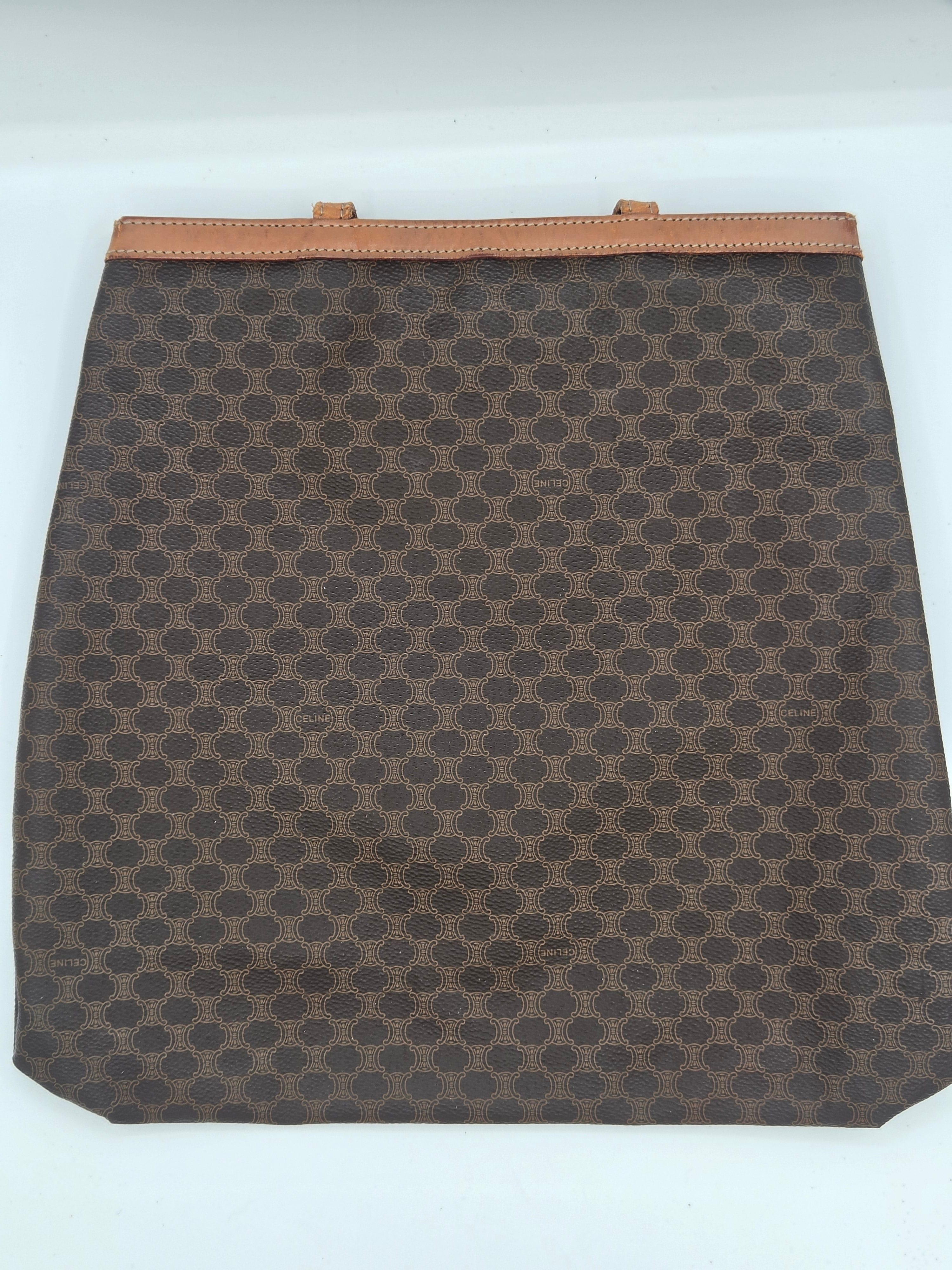 A brown and beige monogram canvas pouch with a tan leather trim on the left side, shown against a plain white background.