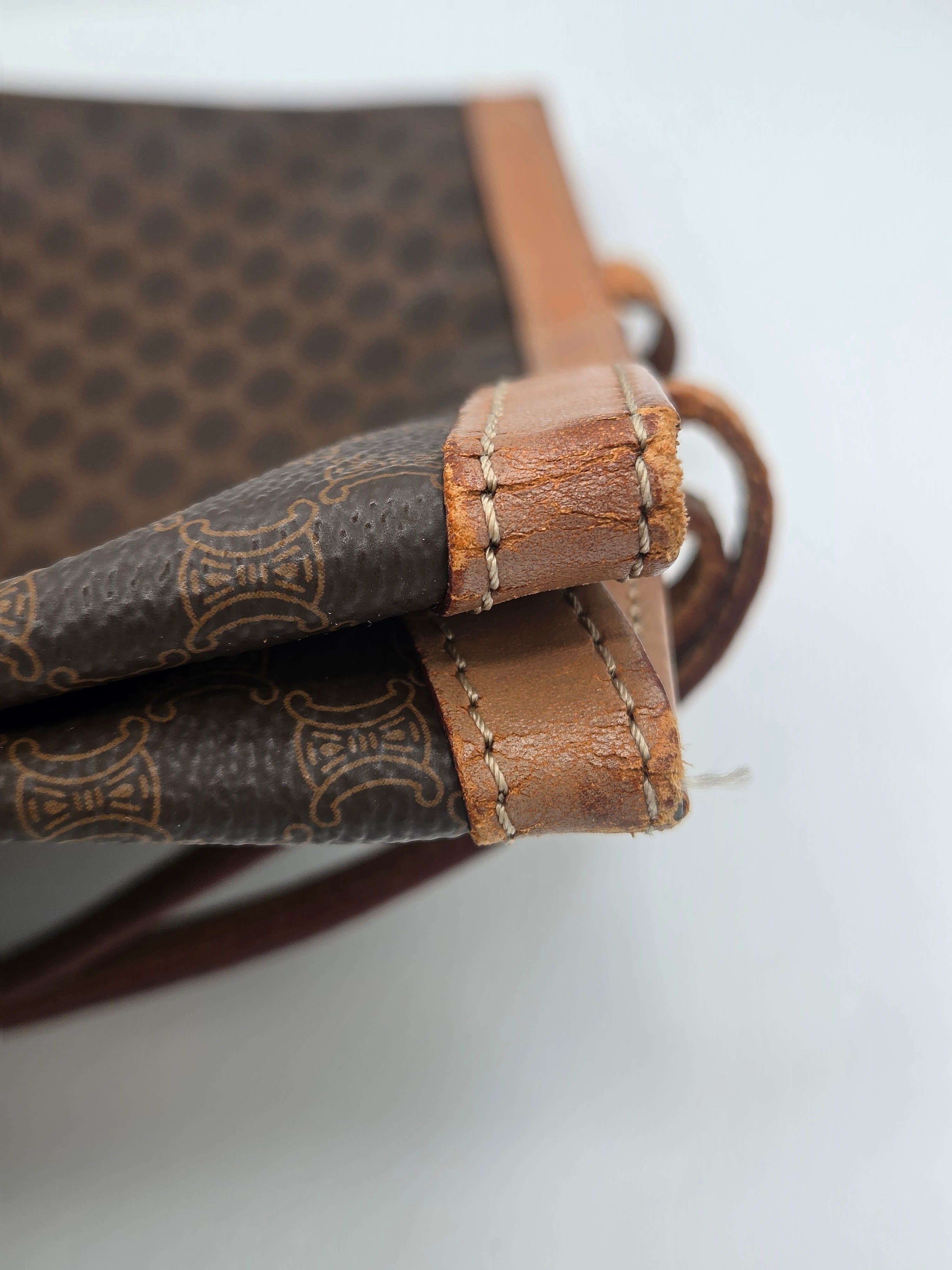 Close-up of a vintage Celine handbag corner showing the brown patterned canvas, tan leather trim, and signature monogram pattern.
