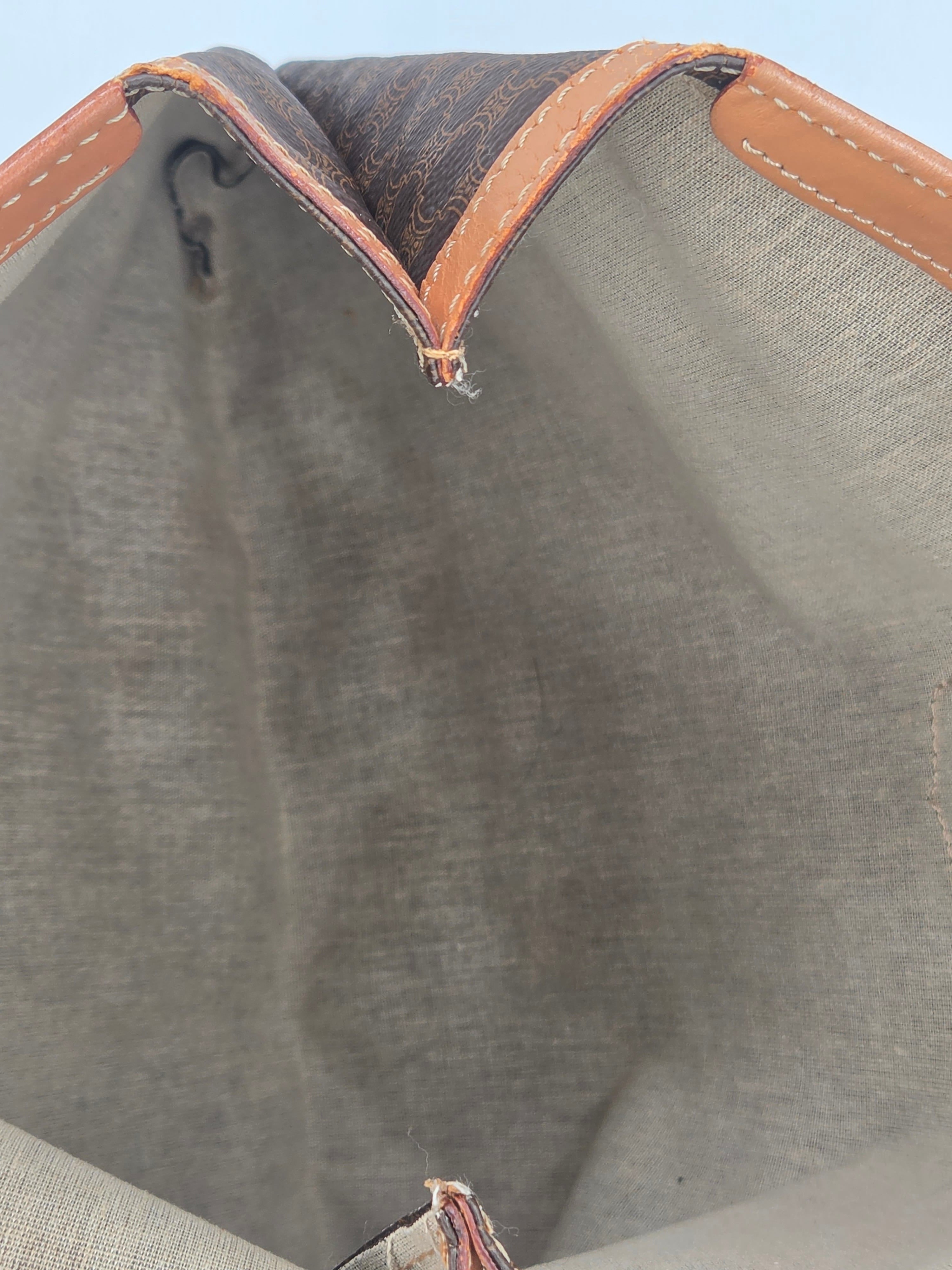 Close-up of the interior of a Louis Vuitton tote bag, showing the gray canvas lining, tan leather trim, and the classic brown monogram canvas exterior corner.