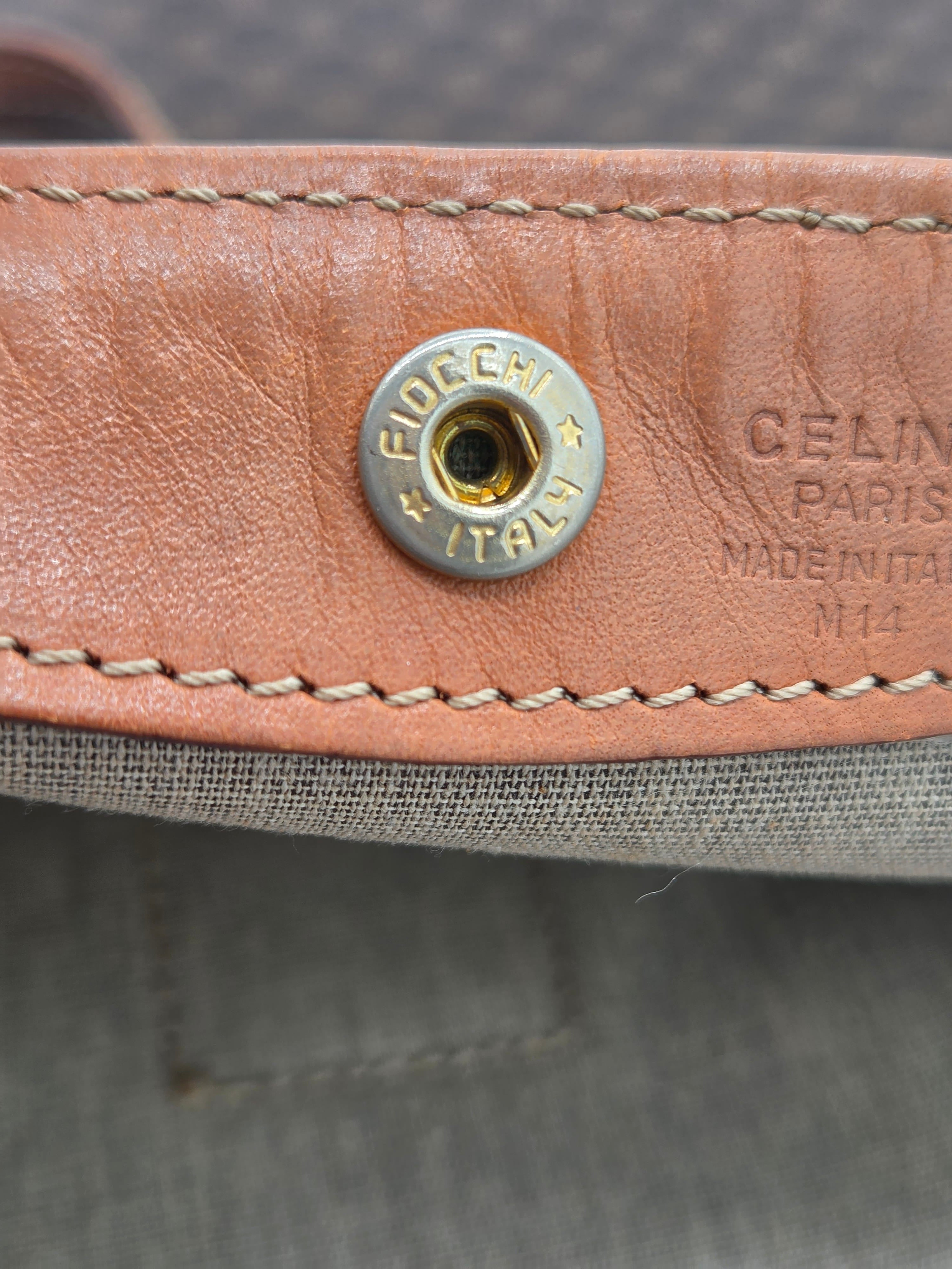 Close-up of a Celine leather strap with a silver-tone metal snap button and white stitching, showing the embossed CELINE PARIS branding.