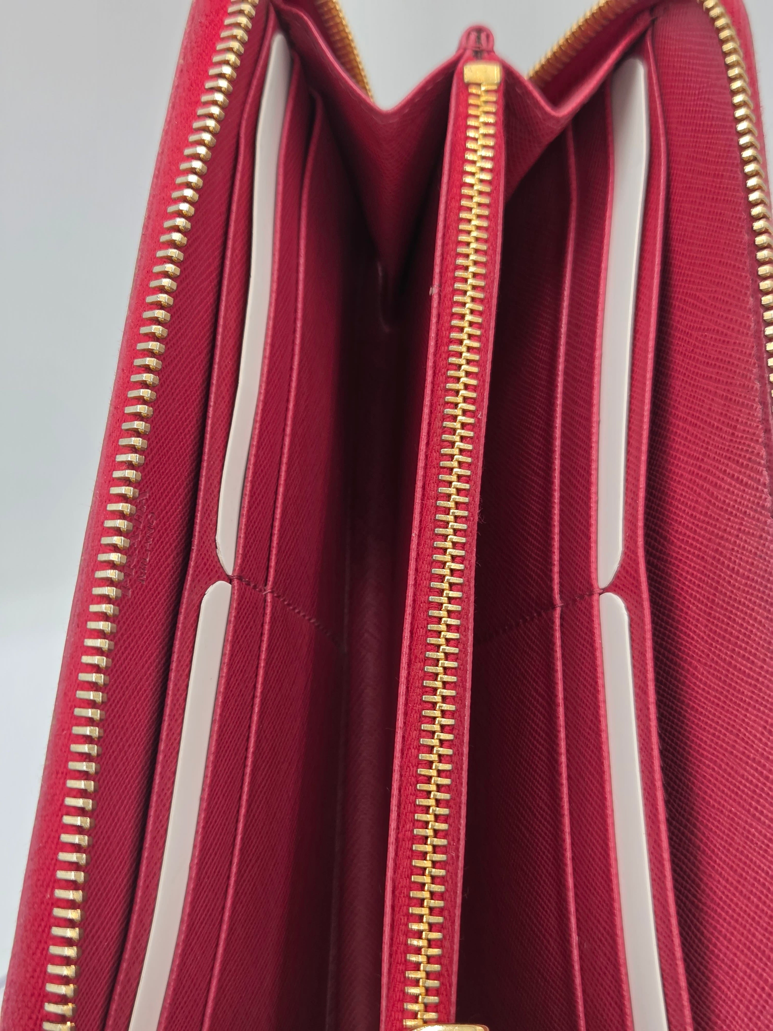 Close-up of the interior of a burgundy zip-around wallet or long wallet, showing multiple card slots, a gold-tone zipper, and white interior lining.