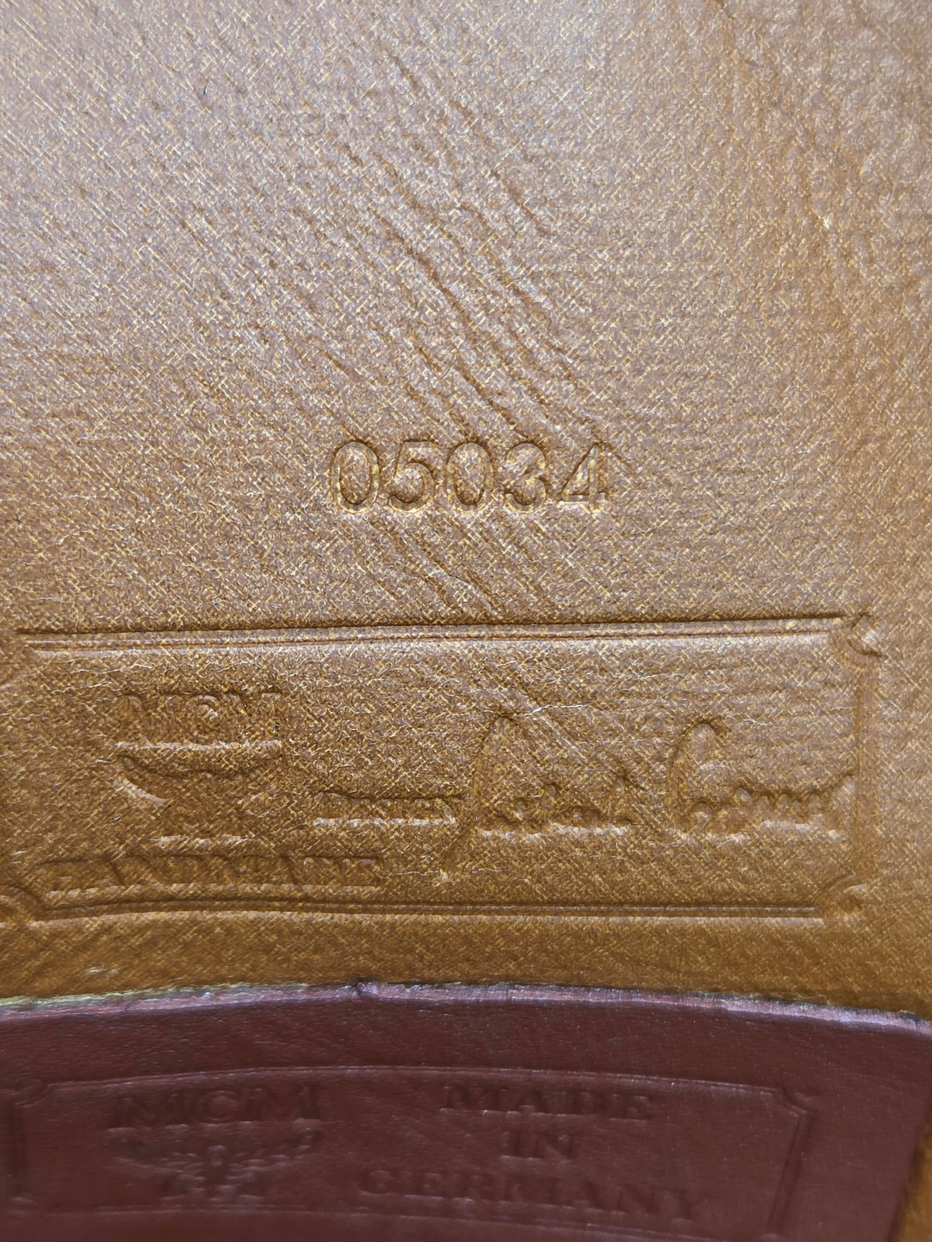 Close-up of a tan textured leather interior with embossed stamped markings including the number 05034 and a rectangular label area with script and logo text.