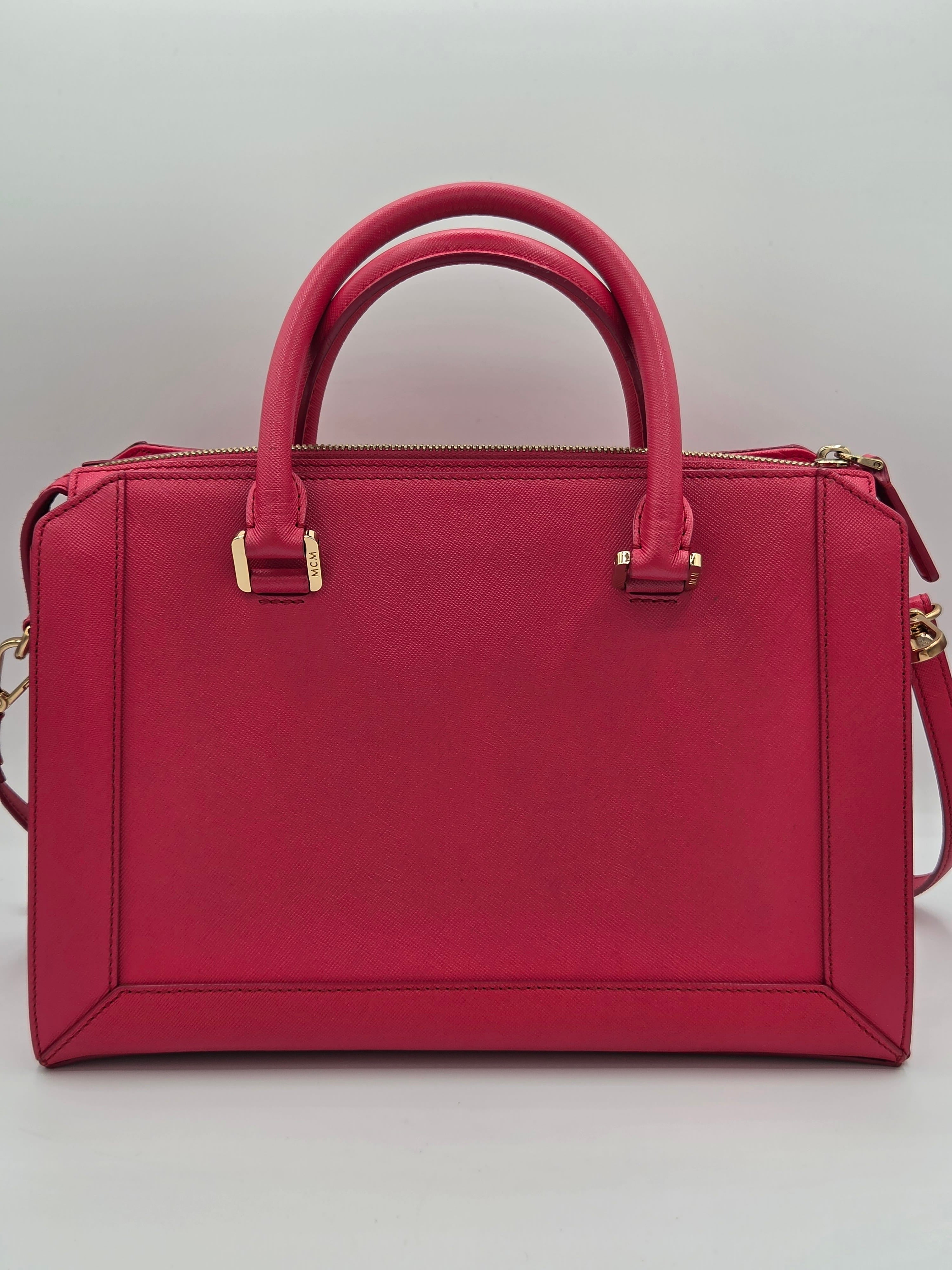 A structured rectangular handbag in deep red leather with double top handles, gold-tone hardware, and a shoulder strap, shown from a top-down view on a light gray background.