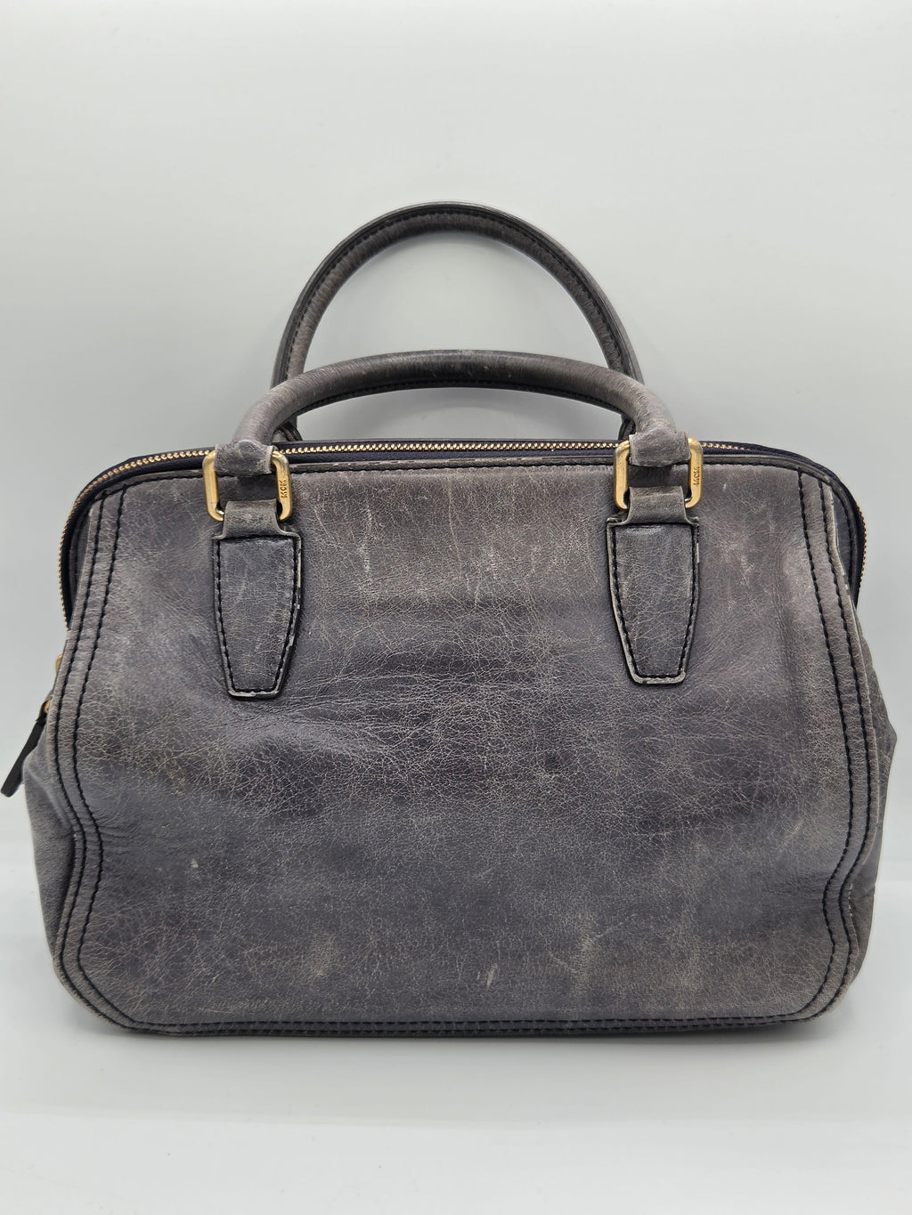A distressed dark gray leather handbag with gold-tone hardware, featuring dual top handles and a zippered top closure, photographed against a neutral light gray background.