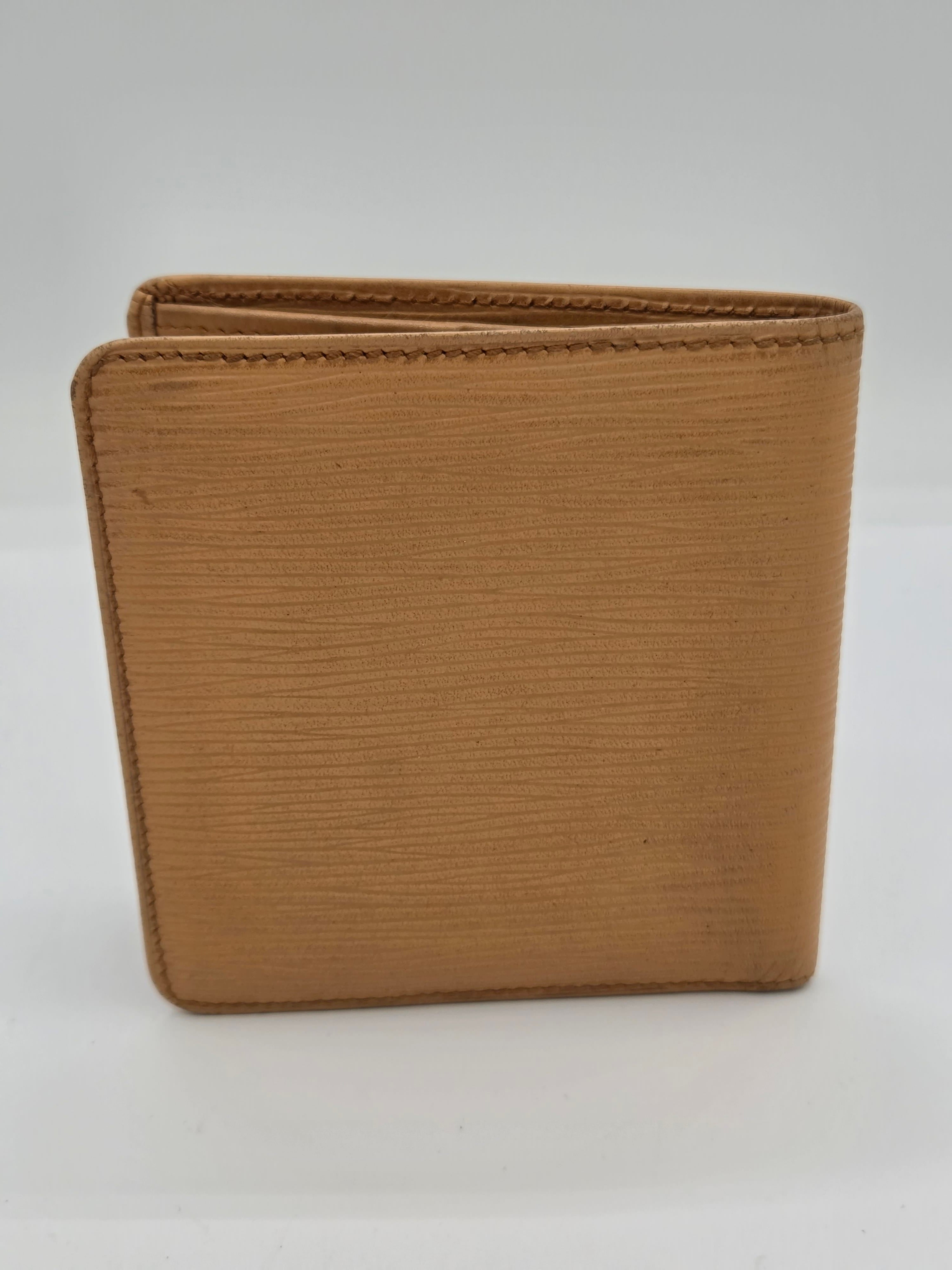 A tan textured leather bi-fold wallet shown closed against a plain white background.