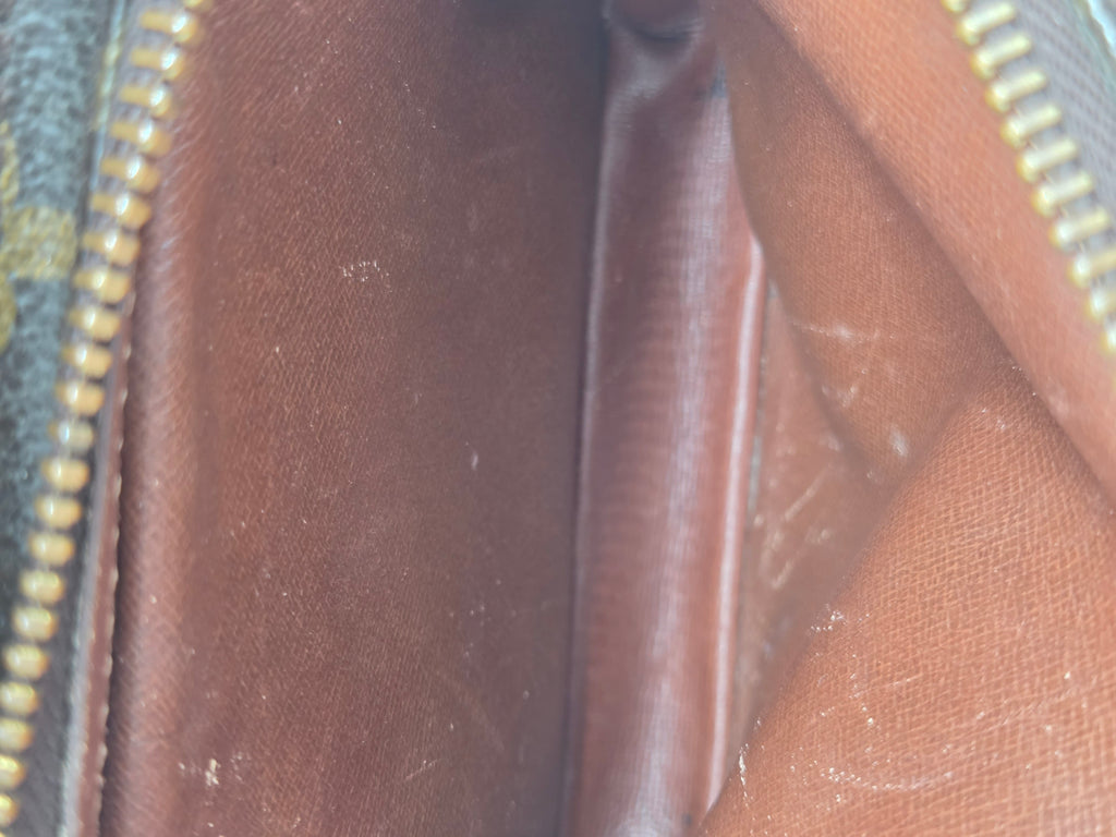 Close-up of the interior lining of a brown coated canvas bag, showing the interior side of a zipper with gold-toned teeth and some visible lint and scuffs on the brown fabric.