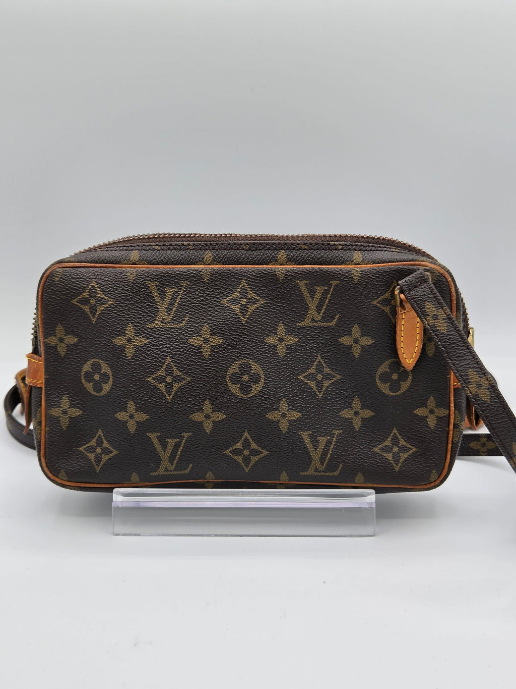 Louis Vuitton monogram canvas shoulder bag in dark brown with tan leather trim, shown hanging against a light gray background.