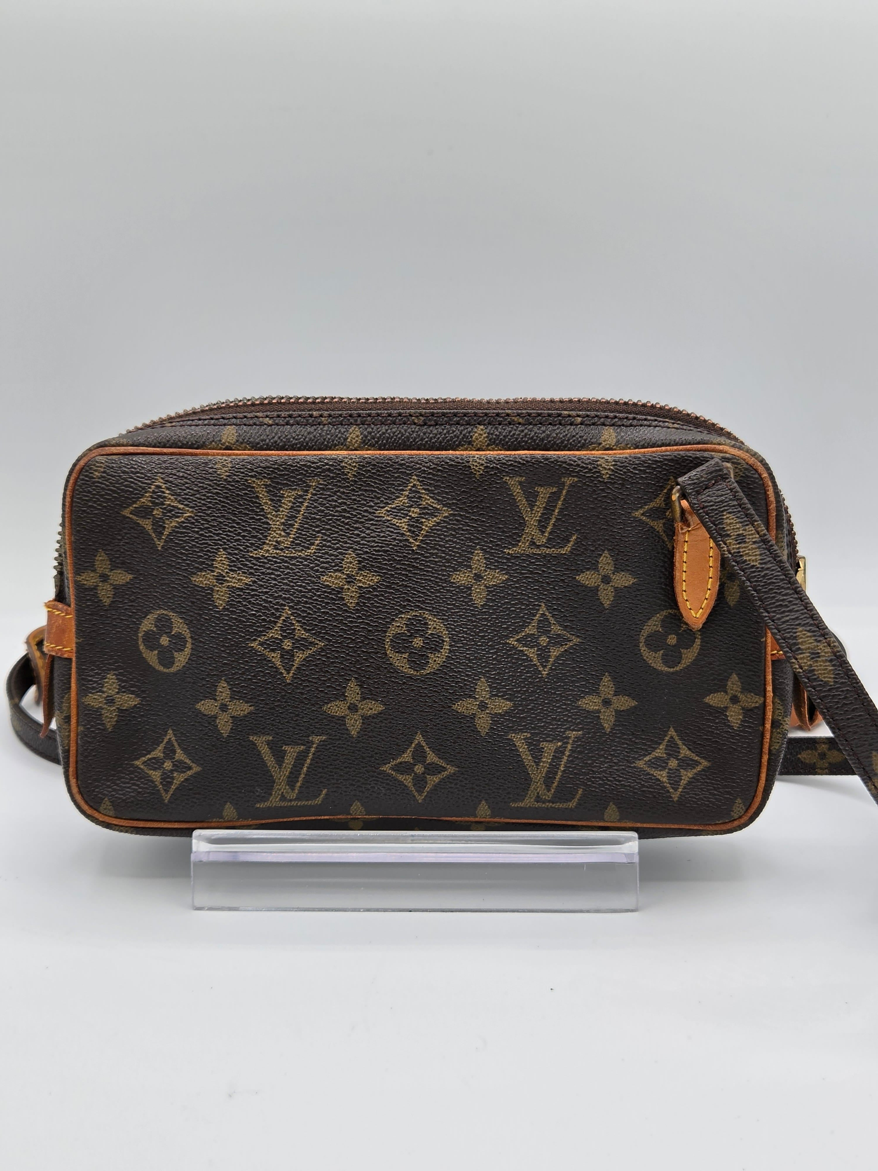 Louis Vuitton monogram canvas shoulder bag in dark brown with tan leather trim, shown hanging against a light gray background.