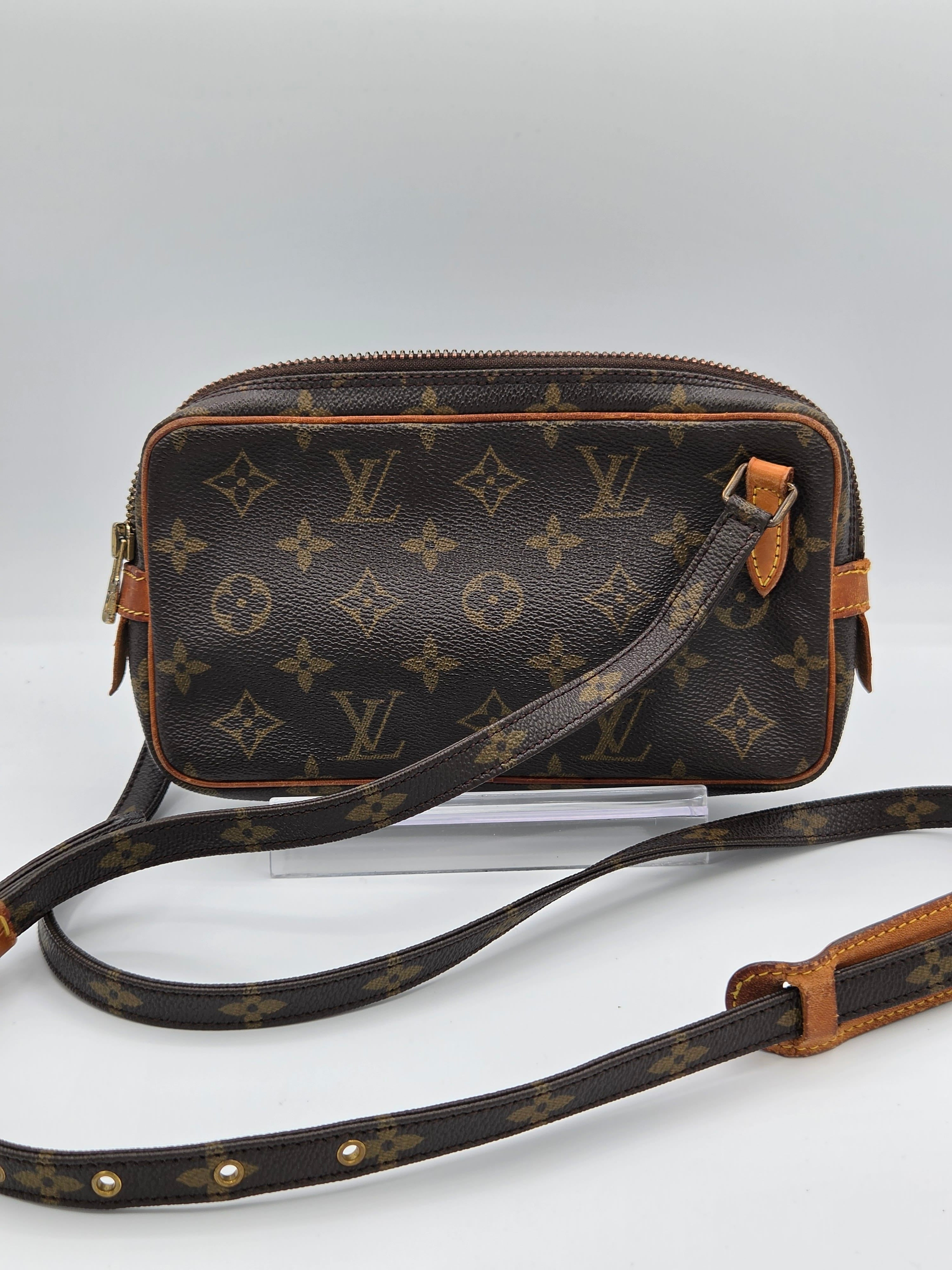 Louis Vuitton monogram canvas camera bag with a brown leather shoulder strap, shown against a plain light background.