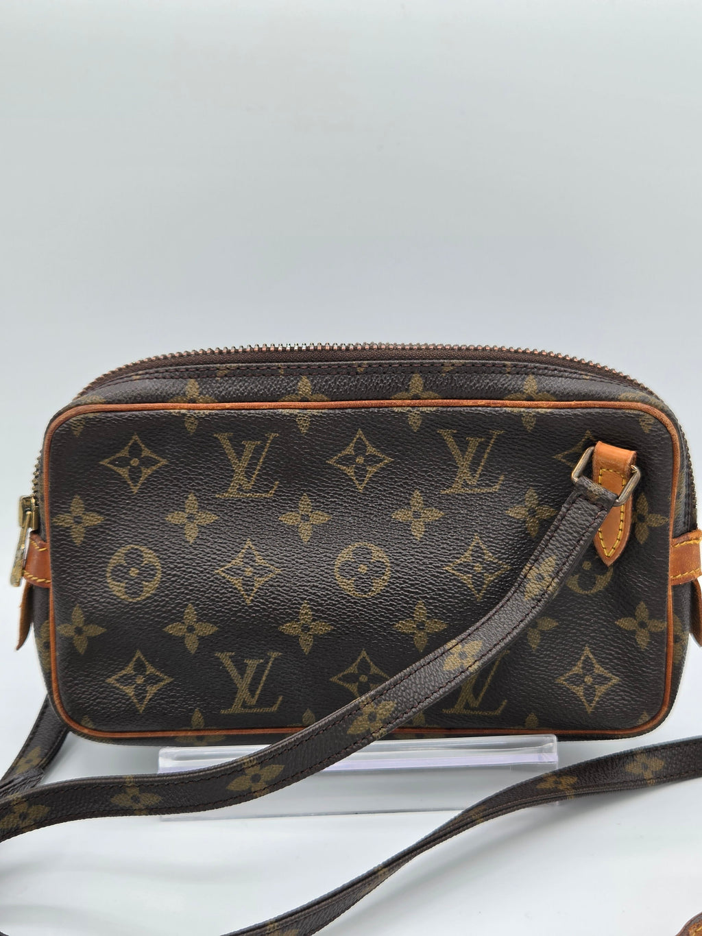Louis Vuitton monogram canvas camera bag in dark brown with tan leather trim and a matching shoulder strap, shown against a light gray background.