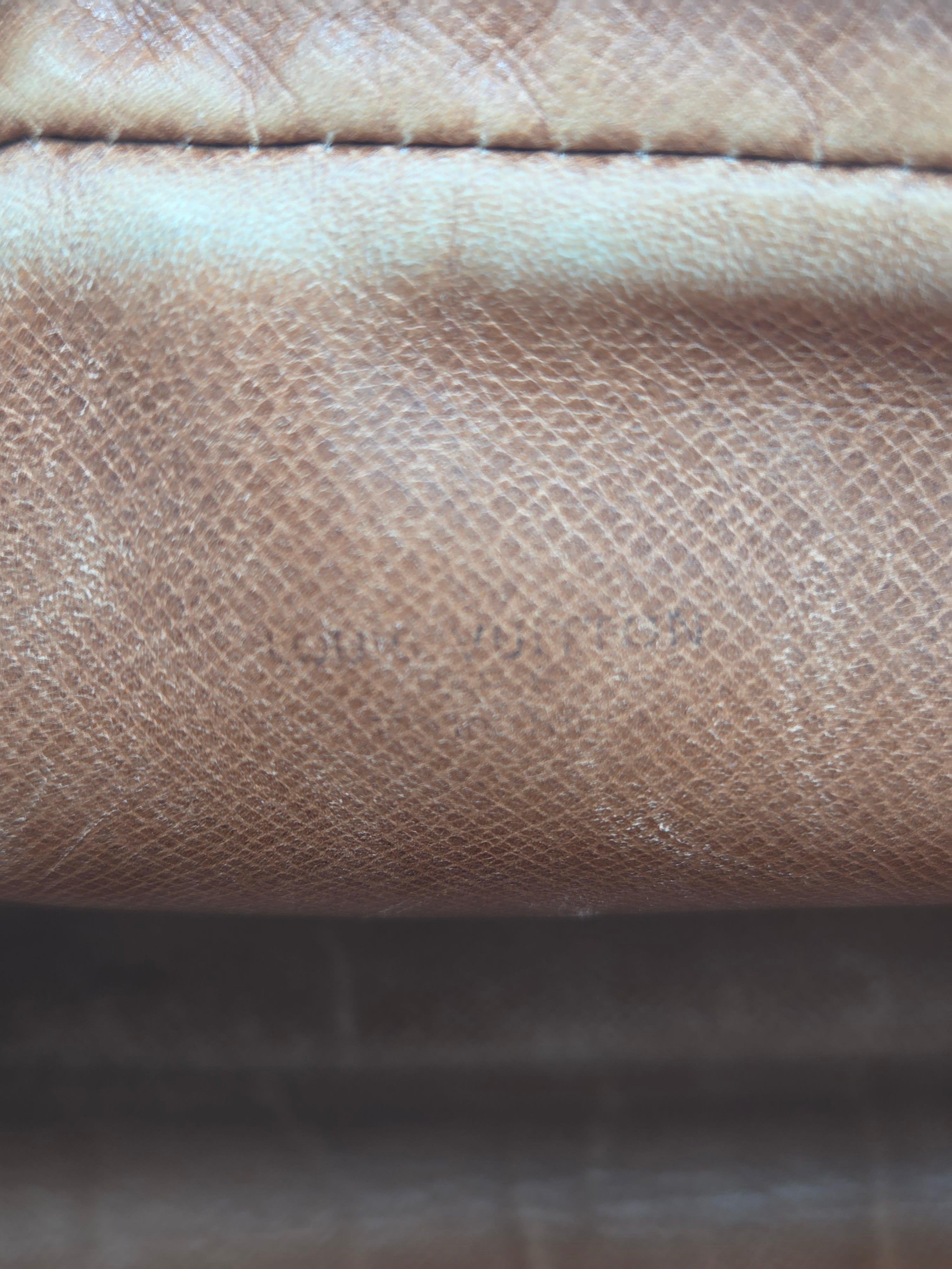 Close-up of a textured leather material in a warm taupe-brown color, showing fine grain and a vertical stitched seam.