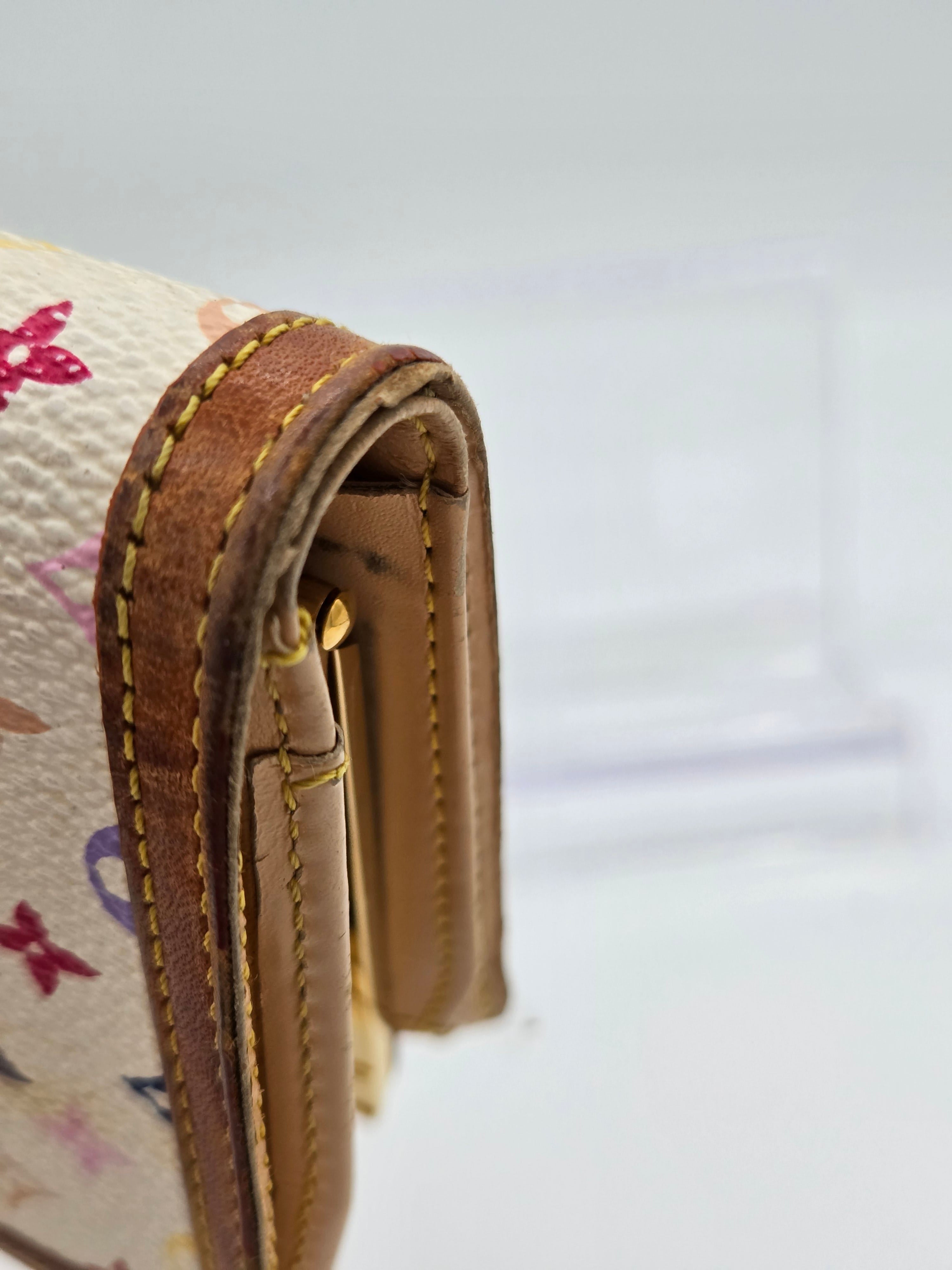 Close-up of a Louis Vuitton handbag corner showing the tan leather trim, gold-tone hardware, and part of the cream monogram canvas.