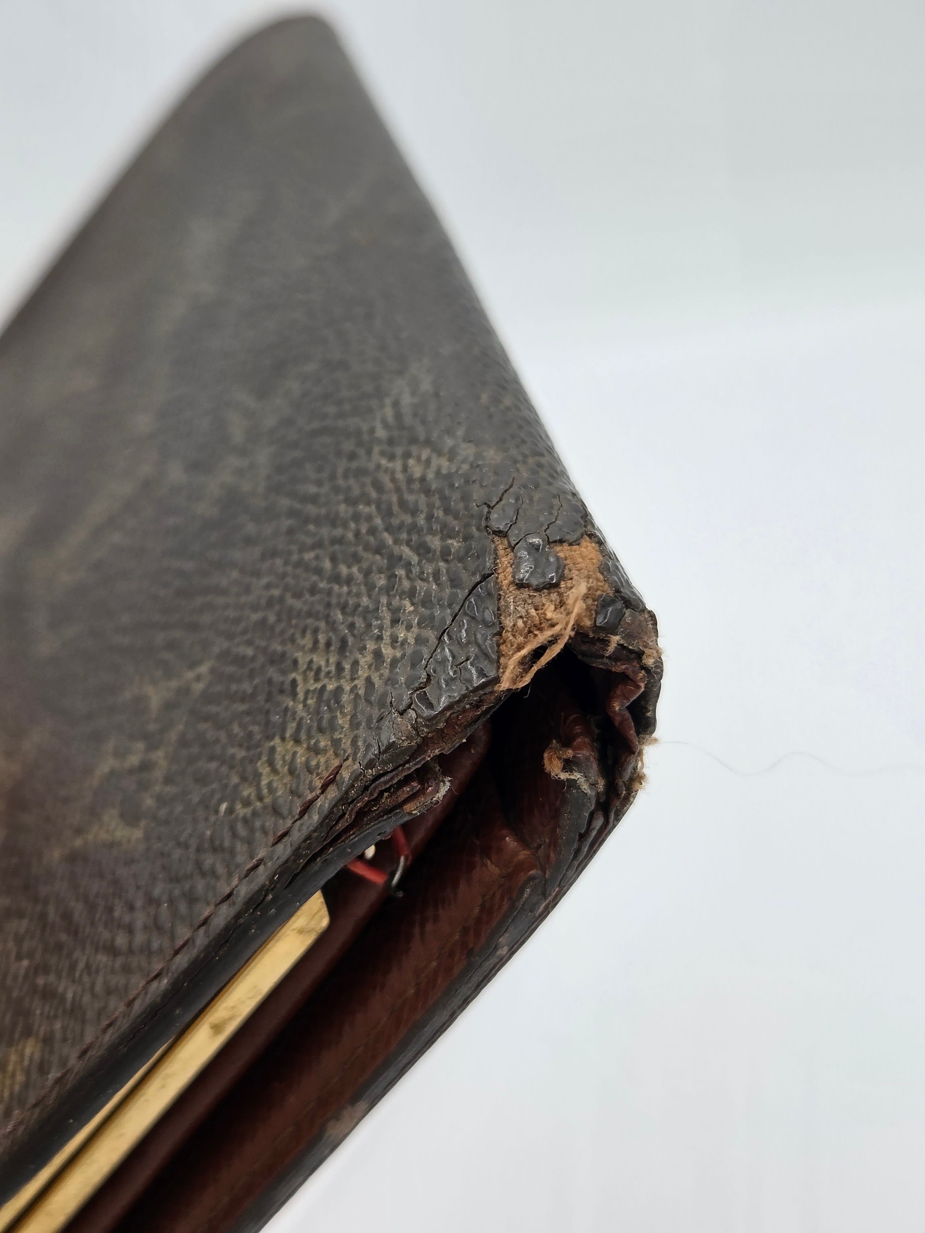 A close-up of a heavily worn brown leather wallet corner with severe tearing, frayed edges, and exposed interior layers on a plain white background.