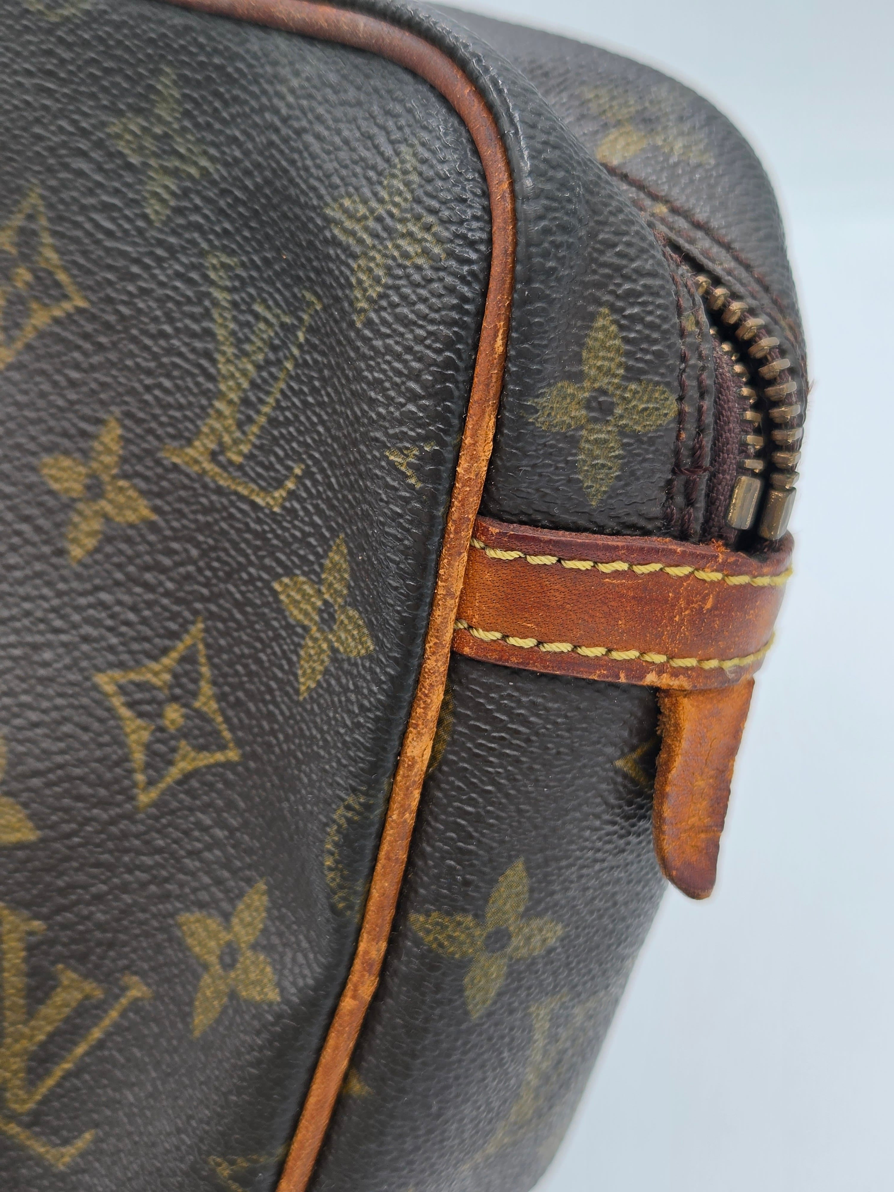 Close-up of a Louis Vuitton monogram canvas bag showing the classic brown and tan pattern with a brown leather strap and zipper pull.