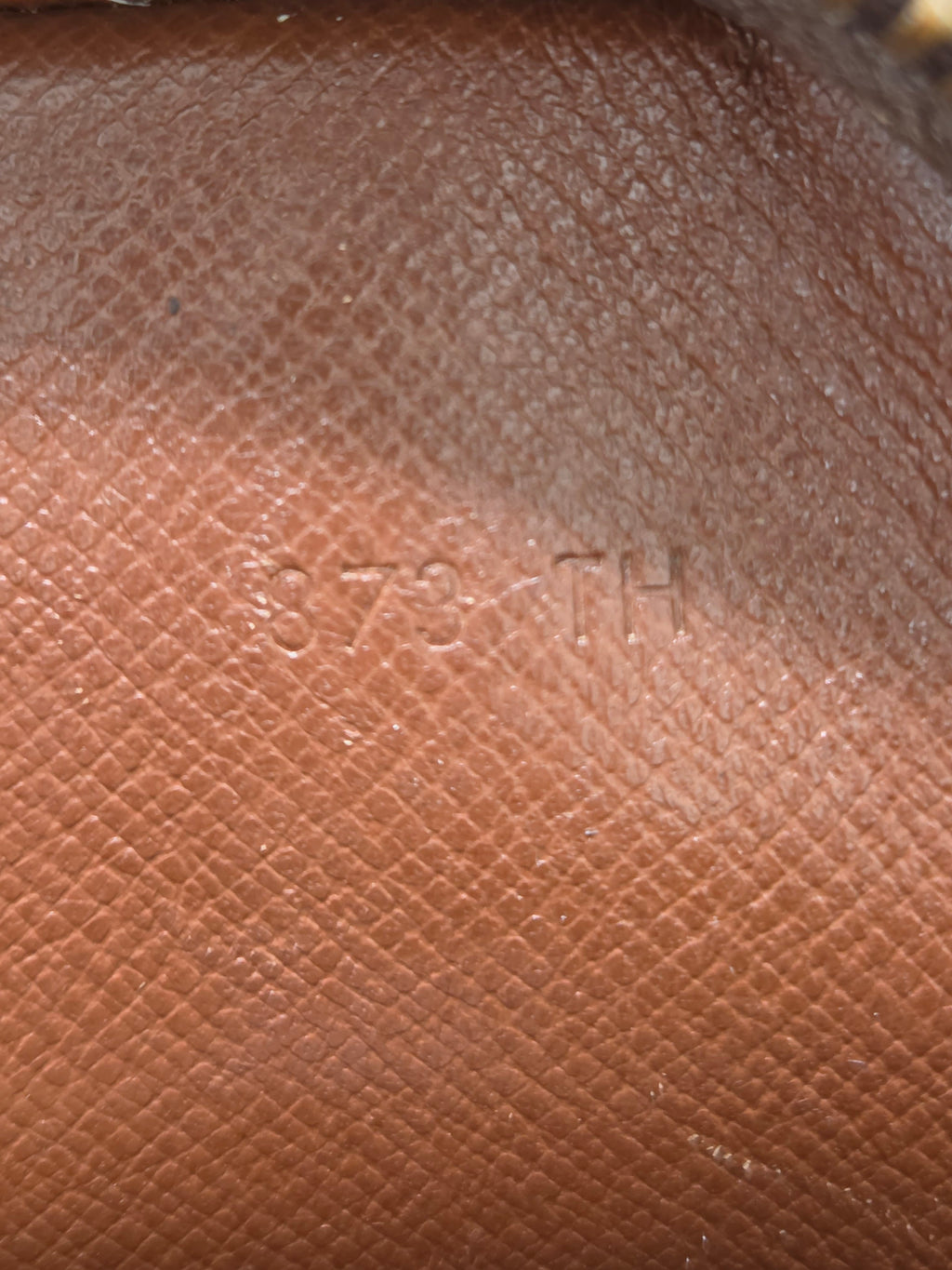 Close-up of textured brown leather with a subtle embossed logo or lettering in the center.