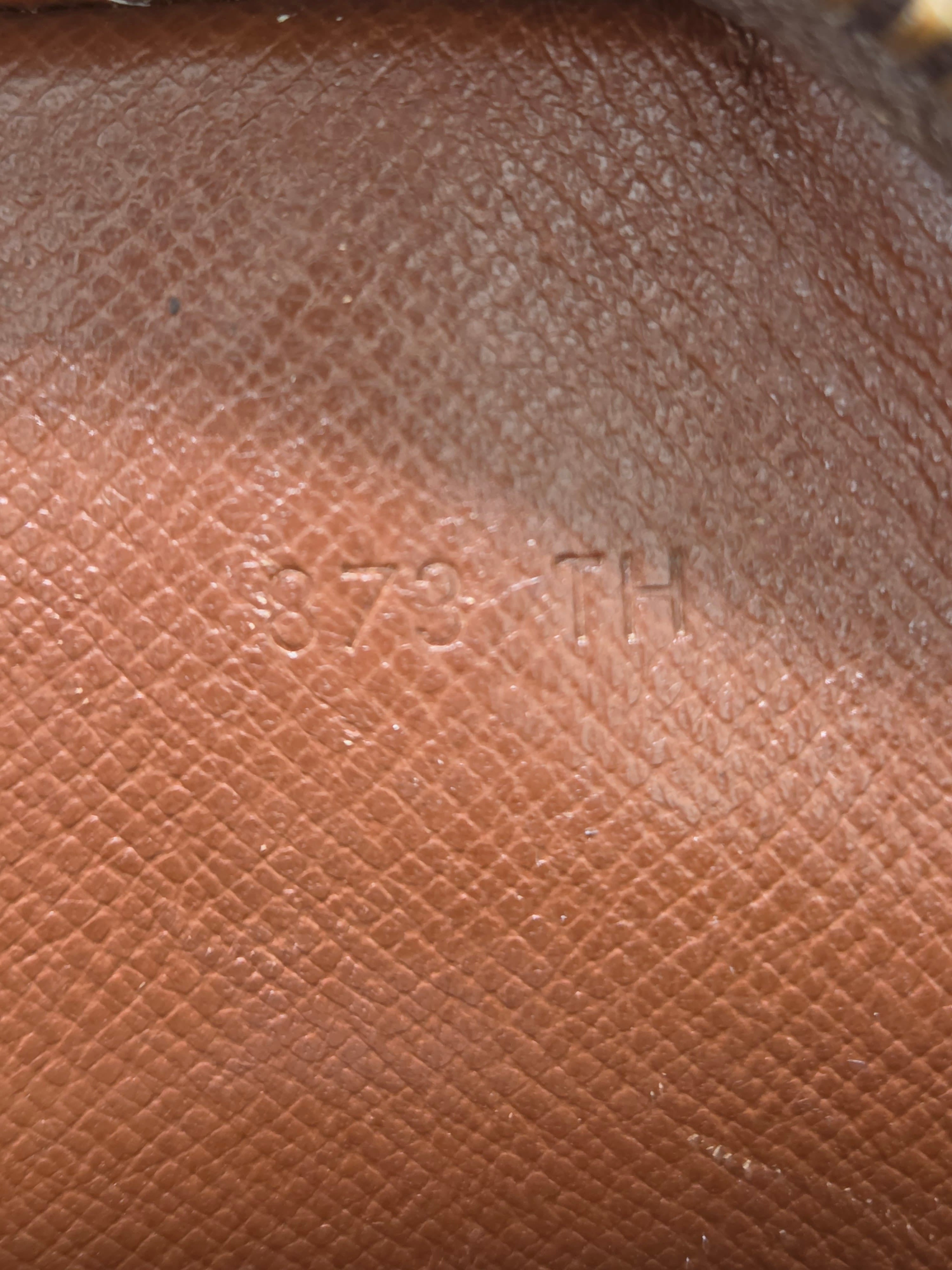 Close-up of textured brown leather with a subtle embossed logo or lettering in the center.