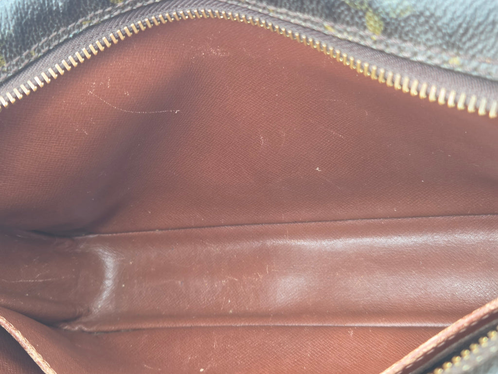 Close-up of the interior of a brown leather zippered pouch or wallet, showing the smooth brown lining and a gold-tone zipper.