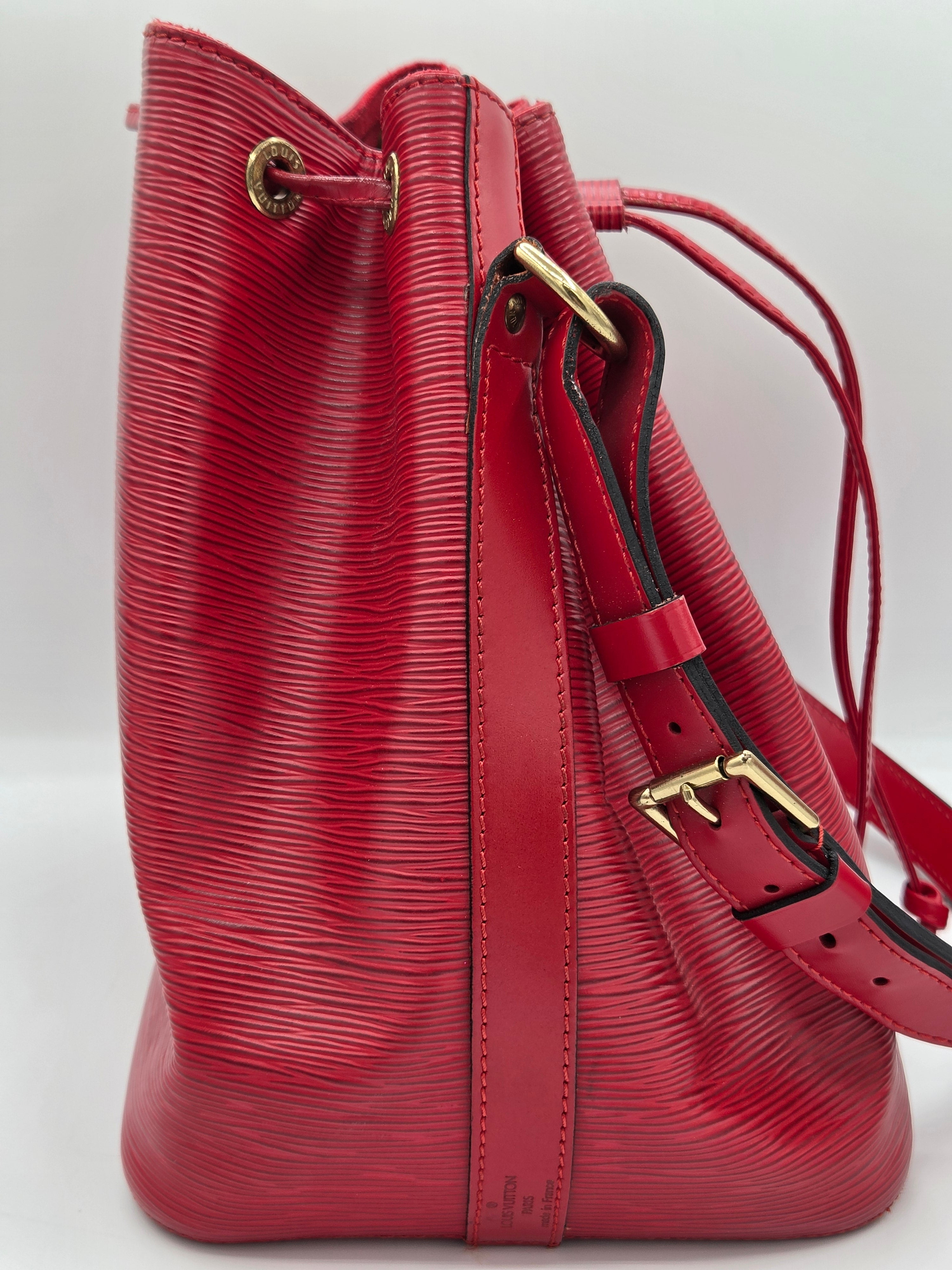 A red textured leather shoulder bag with gold-tone hardware, shown against a plain white background.