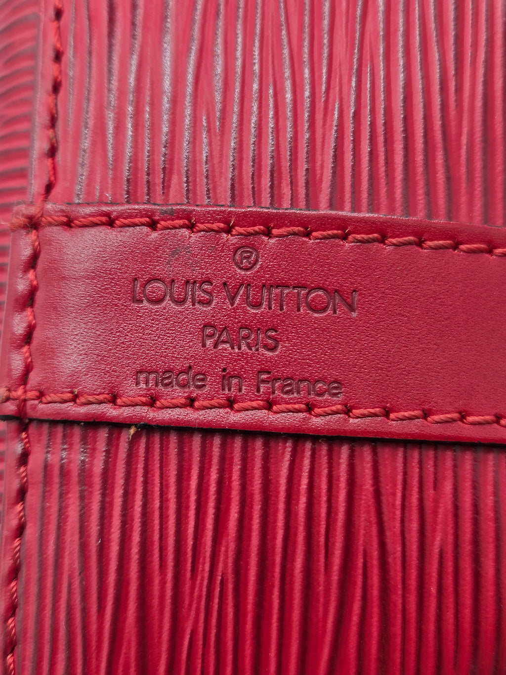 Close-up of a red Louis Vuitton leather detail with embossed branding and texture.