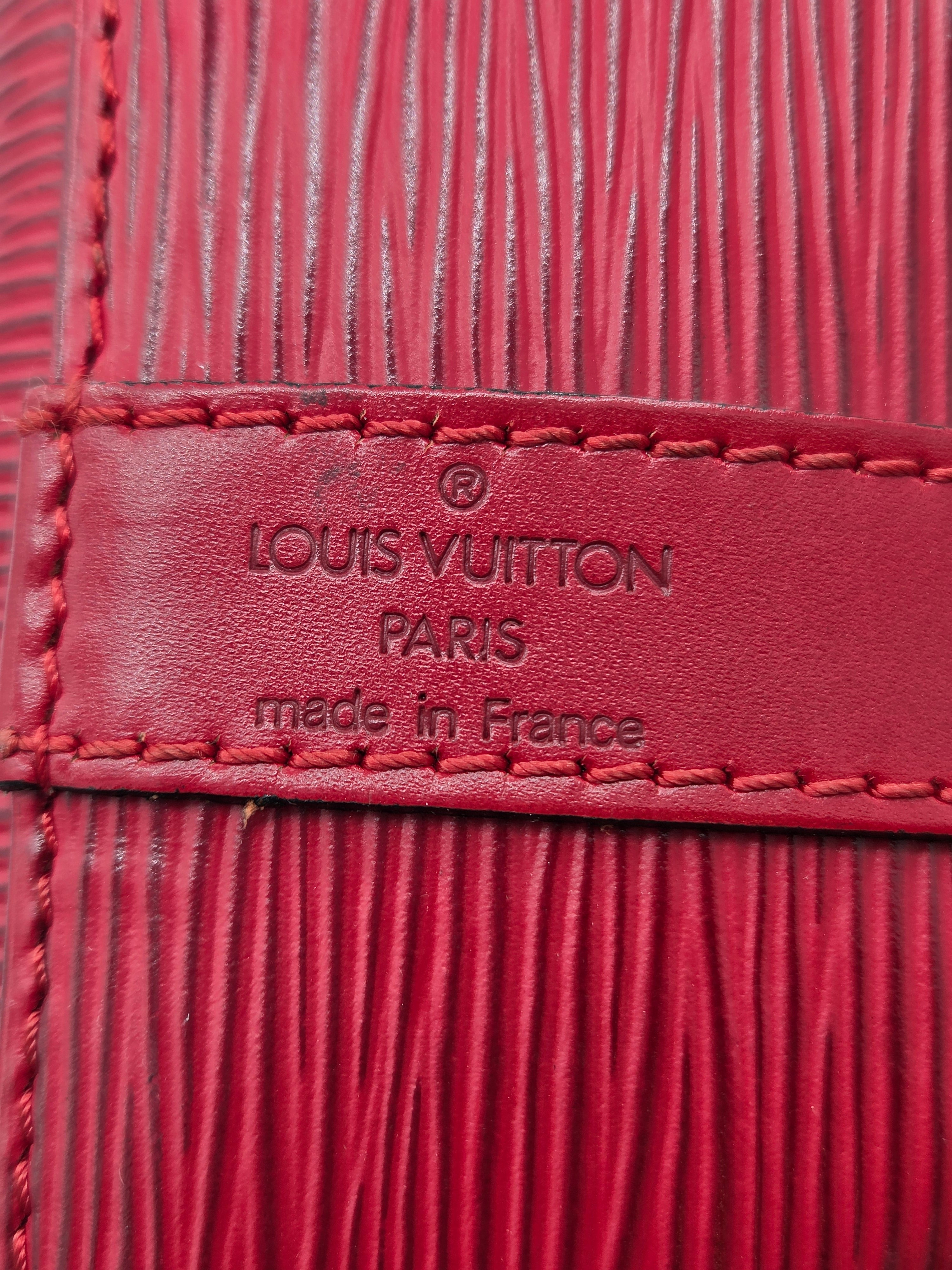 Close-up of a red Louis Vuitton leather detail with embossed branding and texture.